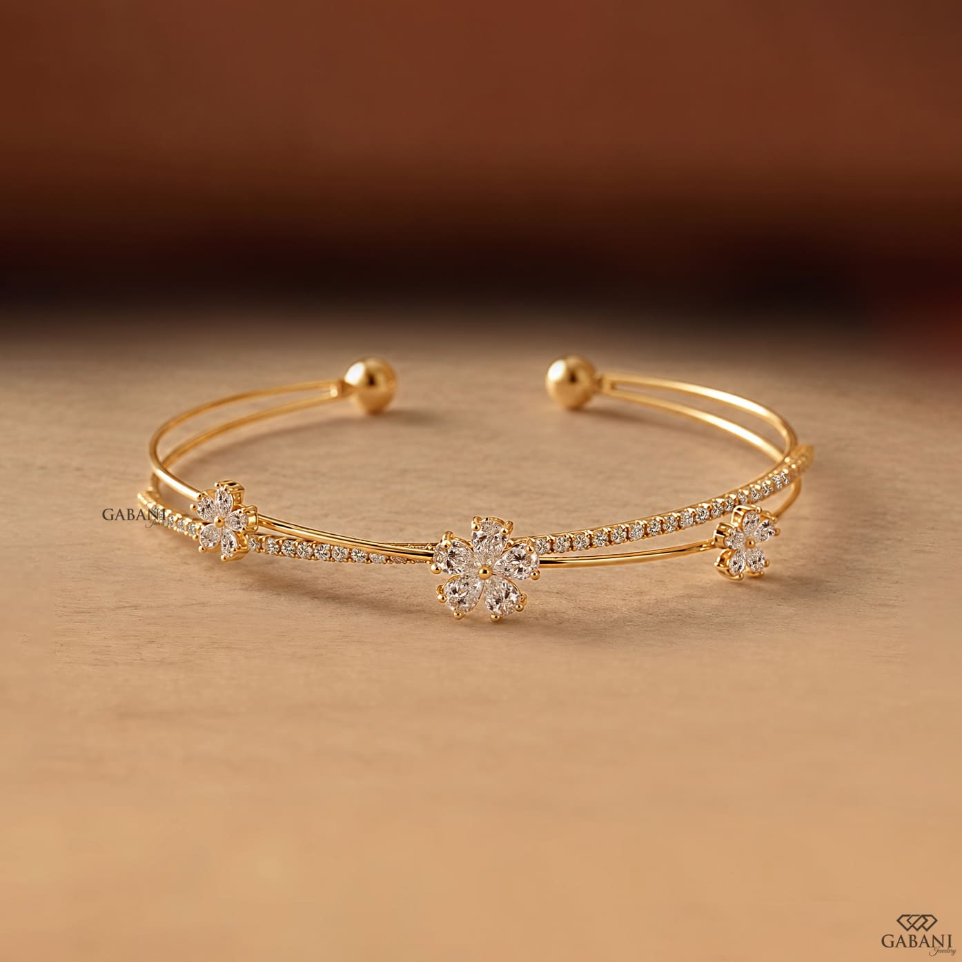 Yellow gold open cuff bangle bracelet featuring three pear cut diamond flower clusters and round pavé diamond accents.