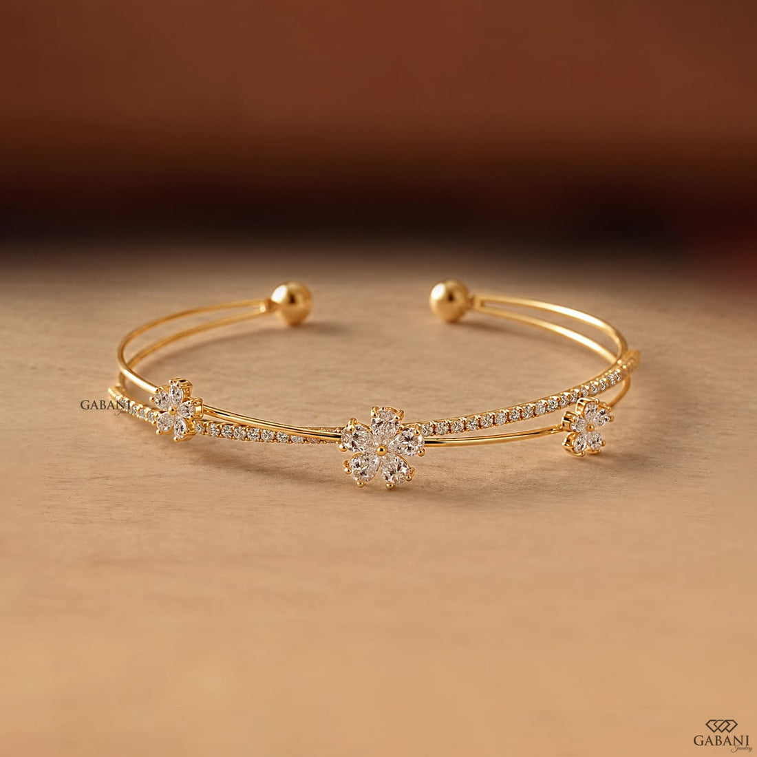 Yellow gold open cuff bangle bracelet featuring three pear cut diamond flower clusters and round pavé diamond accents.