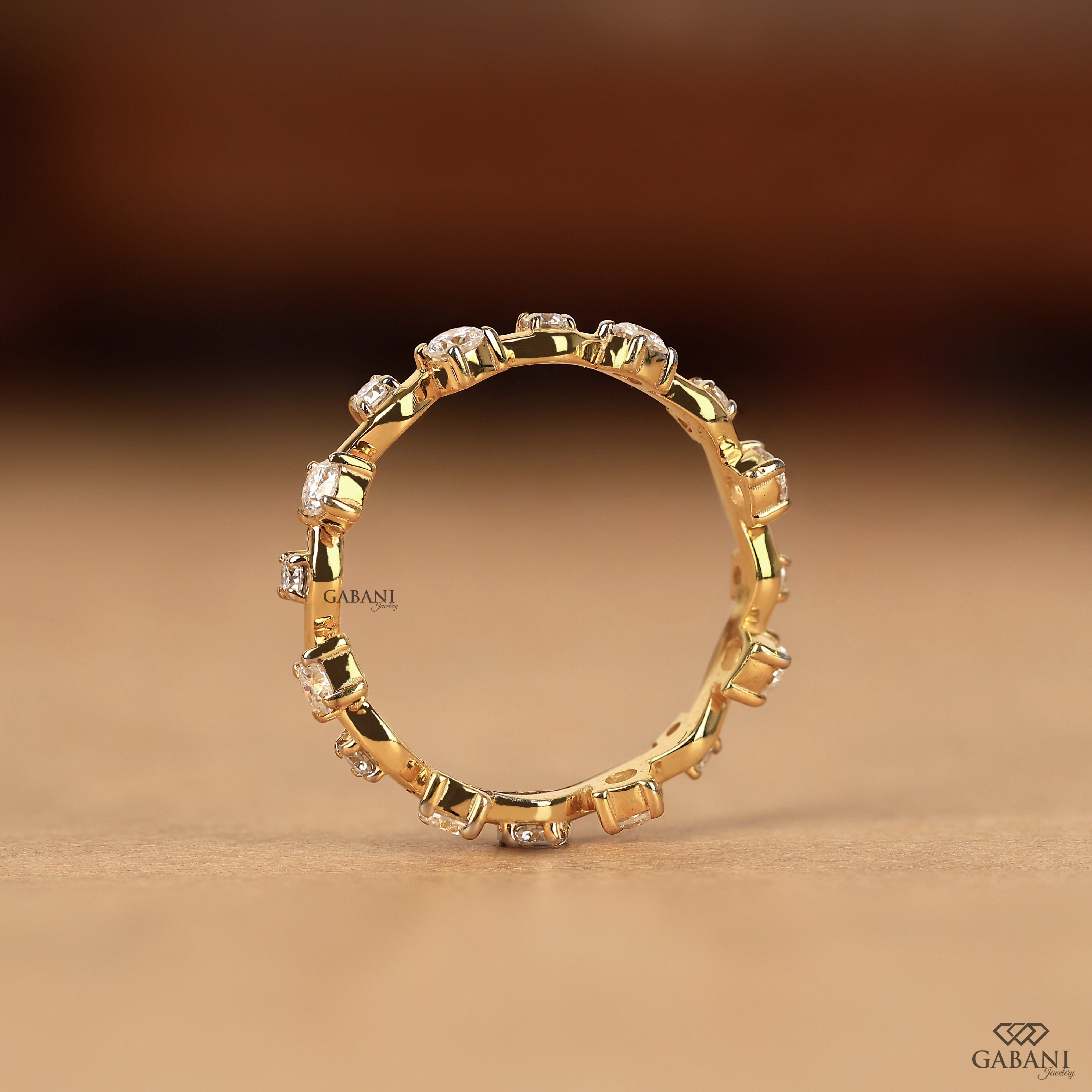 a round lab grown diamond zigzag eternity band in 14K yellow gold, featuring alternating round diamonds in a unique wave design.