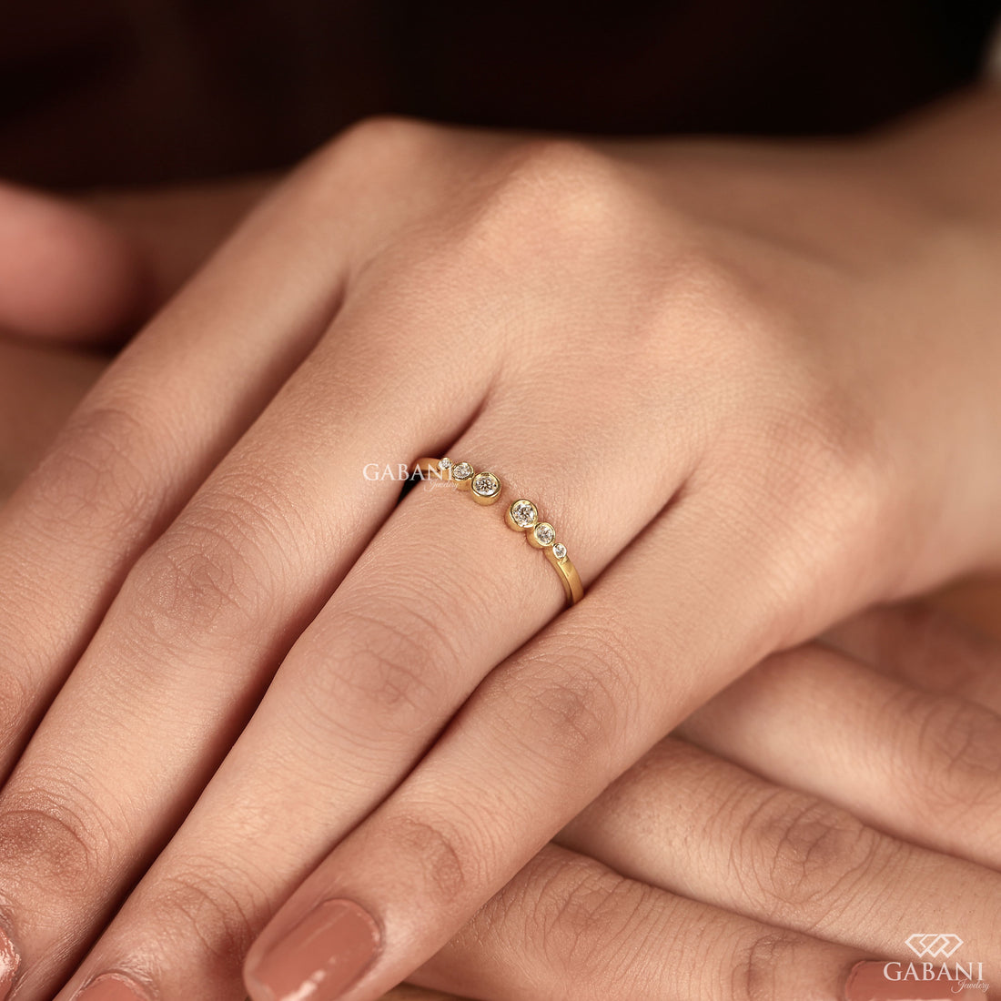a round cut lab grown diamond open cuff band featuring six graduated bezel set diamonds in polished 14K yellow gold, a modern minimalist diamond wedding band by Gabani Jewelry.