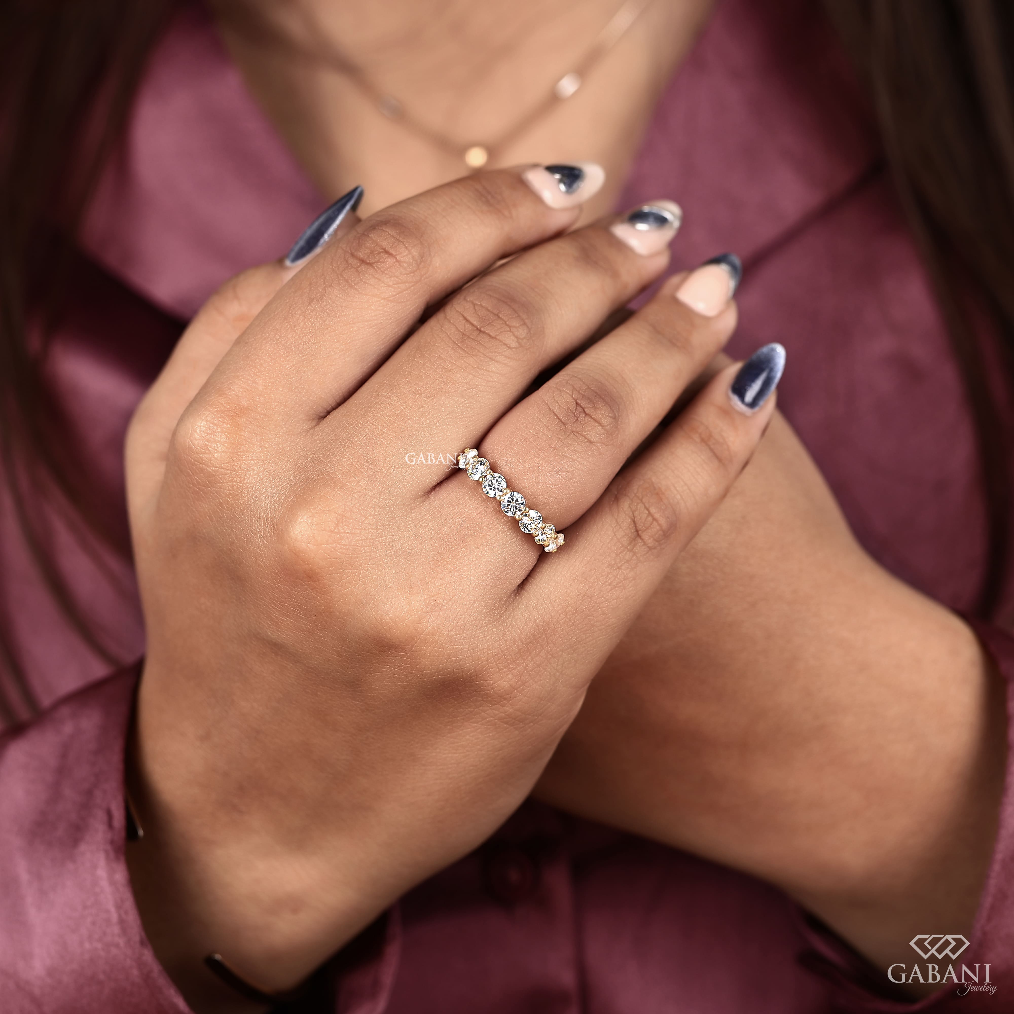 seven round cut lab grown diamonds in a yellow gold half eternity wedding band with open prong settings and a smooth shank.