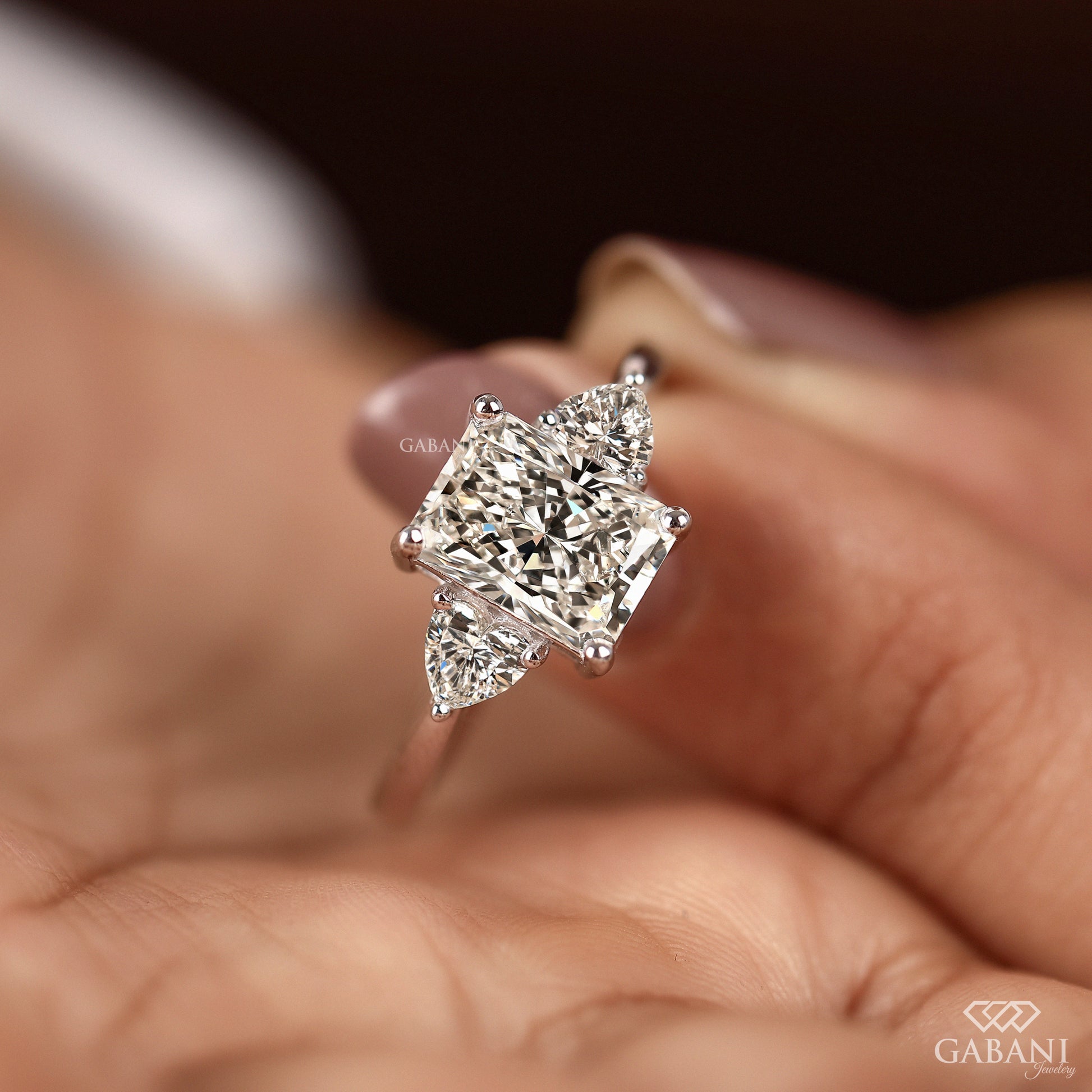 Three stone radiant cut lab grown diamond engagement ring with heart side stones in white gold