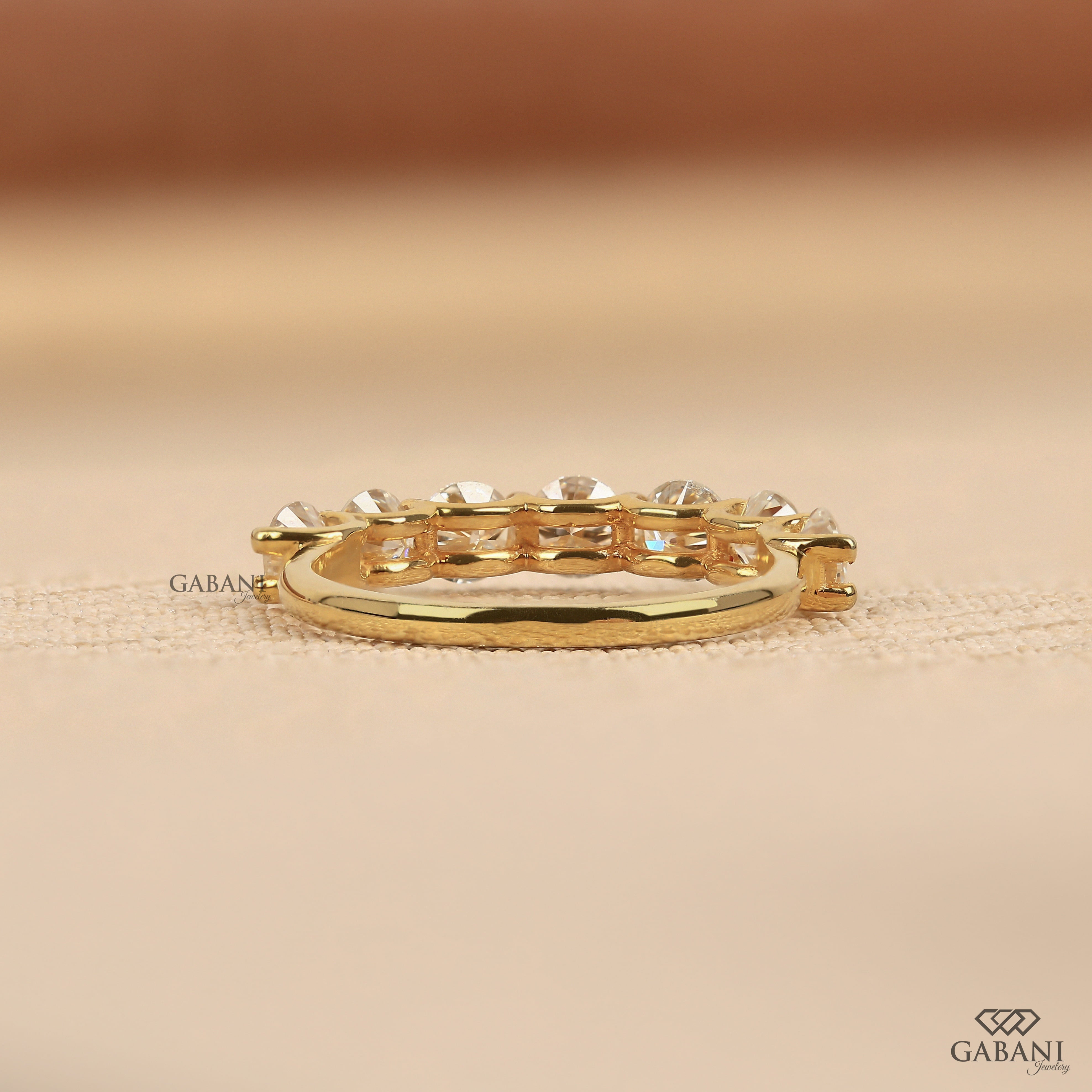 seven round cut lab grown diamonds in a yellow gold half eternity wedding band with open prong settings and a smooth shank.