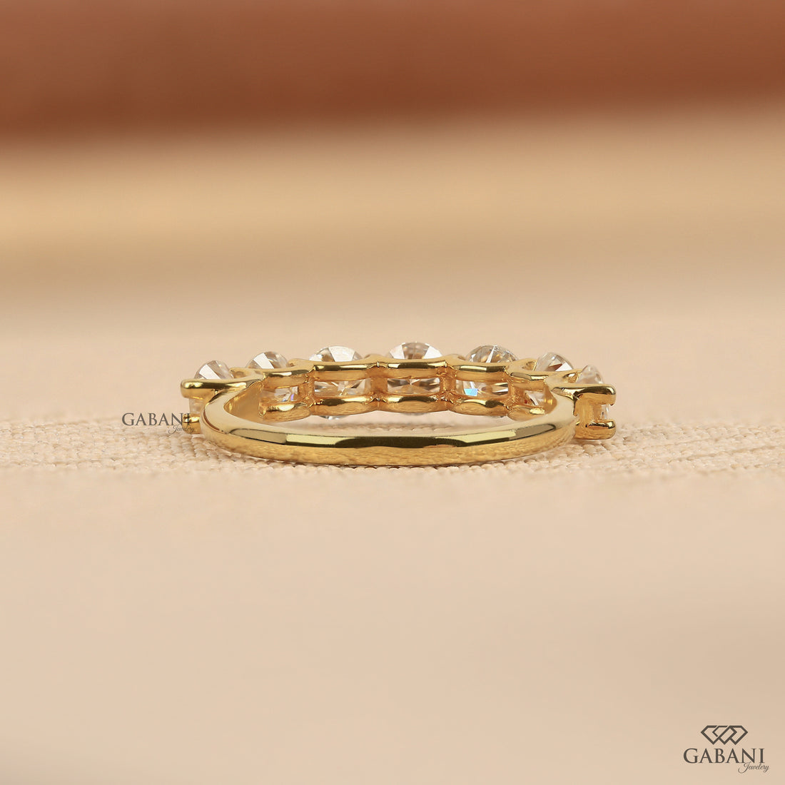 seven round cut lab grown diamonds in a yellow gold half eternity wedding band with open prong settings and a smooth shank.