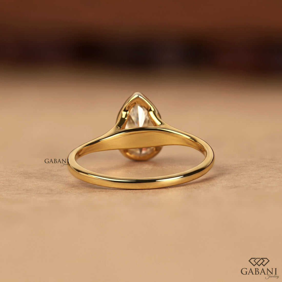 Pear cut diamond solitaire engagement ring with full bezel setting in polished yellow gold