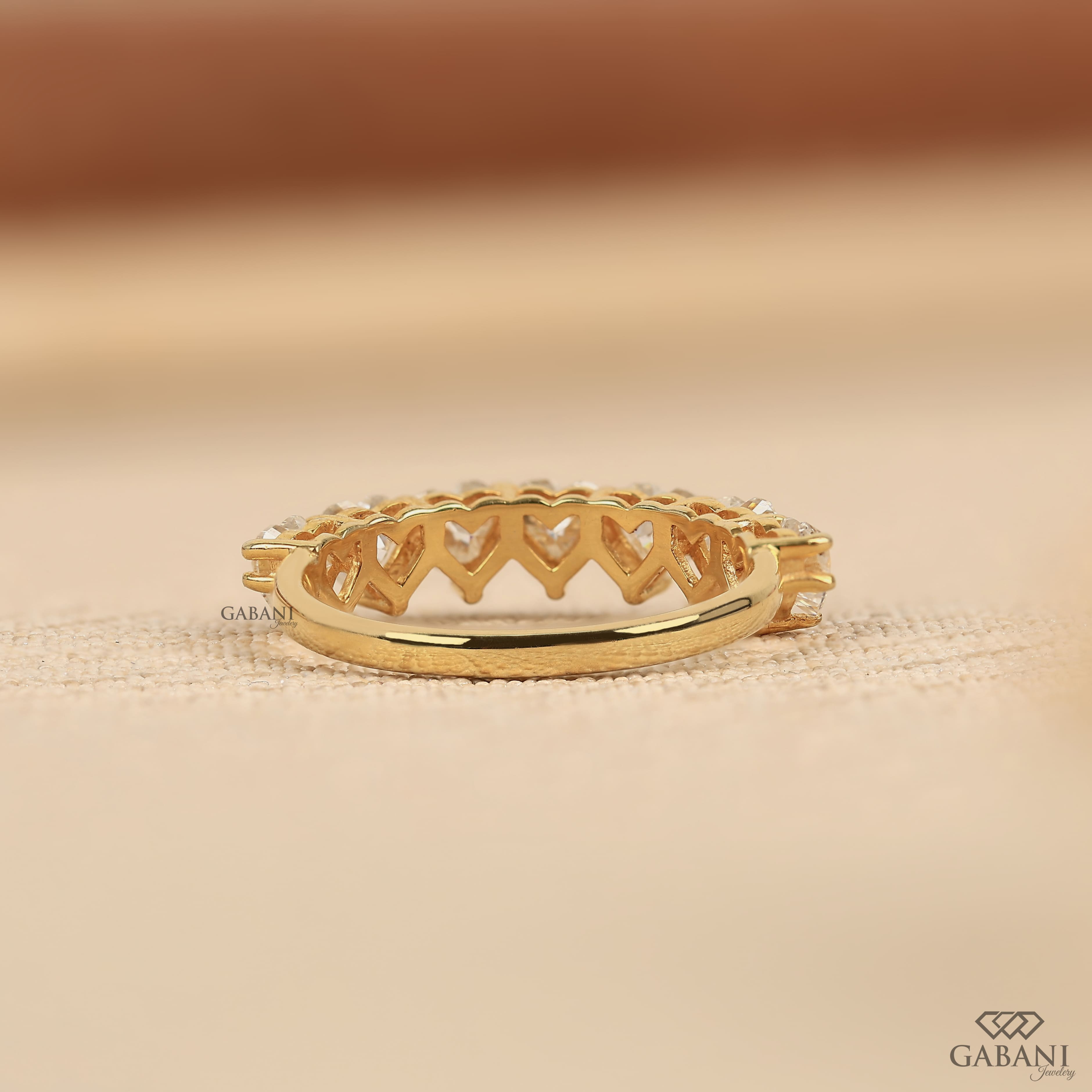 seven heart cut lab grown diamonds in a yellow gold half eternity wedding band with delicate prong settings.