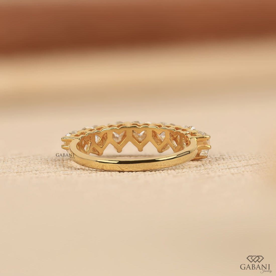 seven heart cut lab grown diamonds in a yellow gold half eternity wedding band with delicate prong settings.