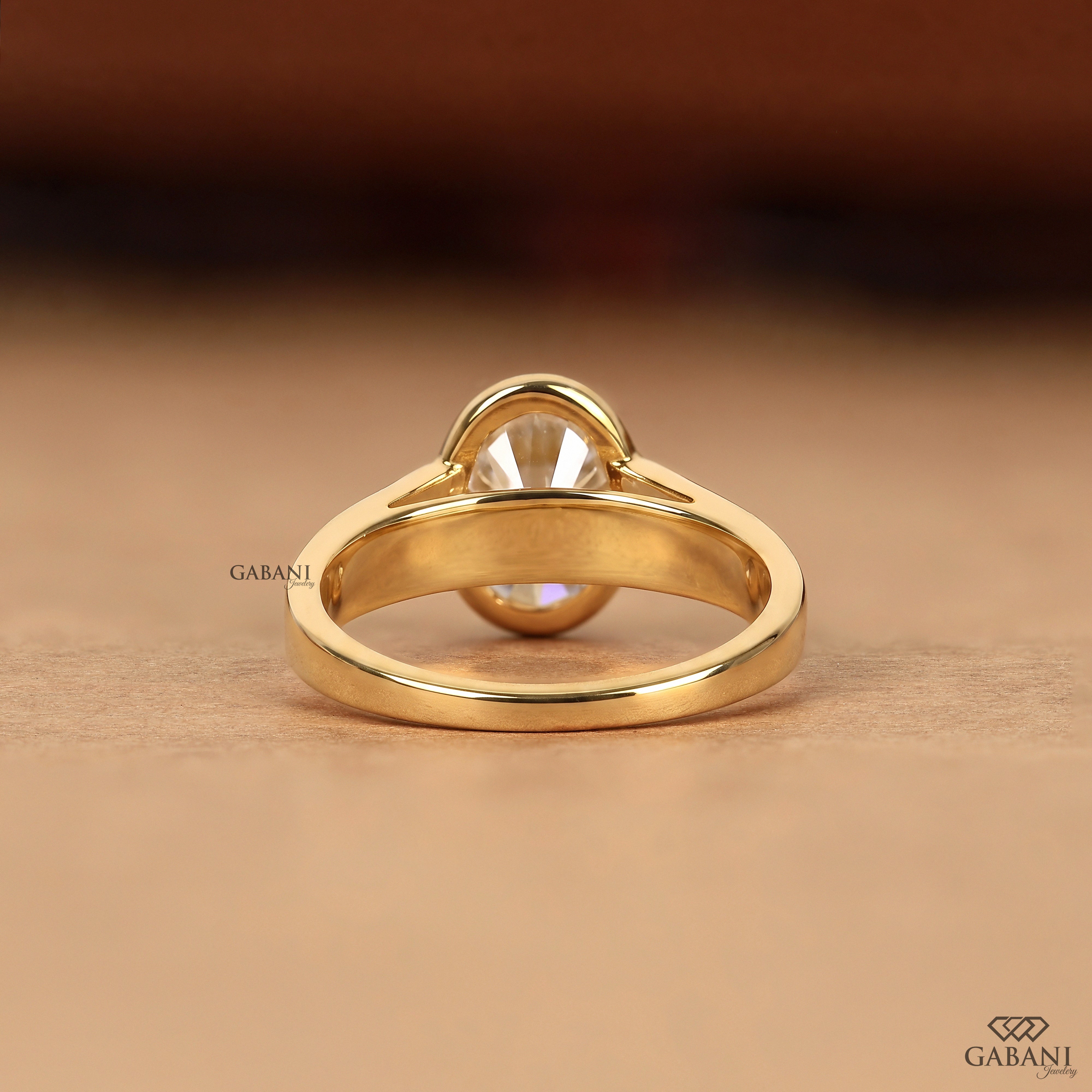 Back view of a three stone oval cut lab grown diamond engagement ring with bezel settings in solid yellow gold