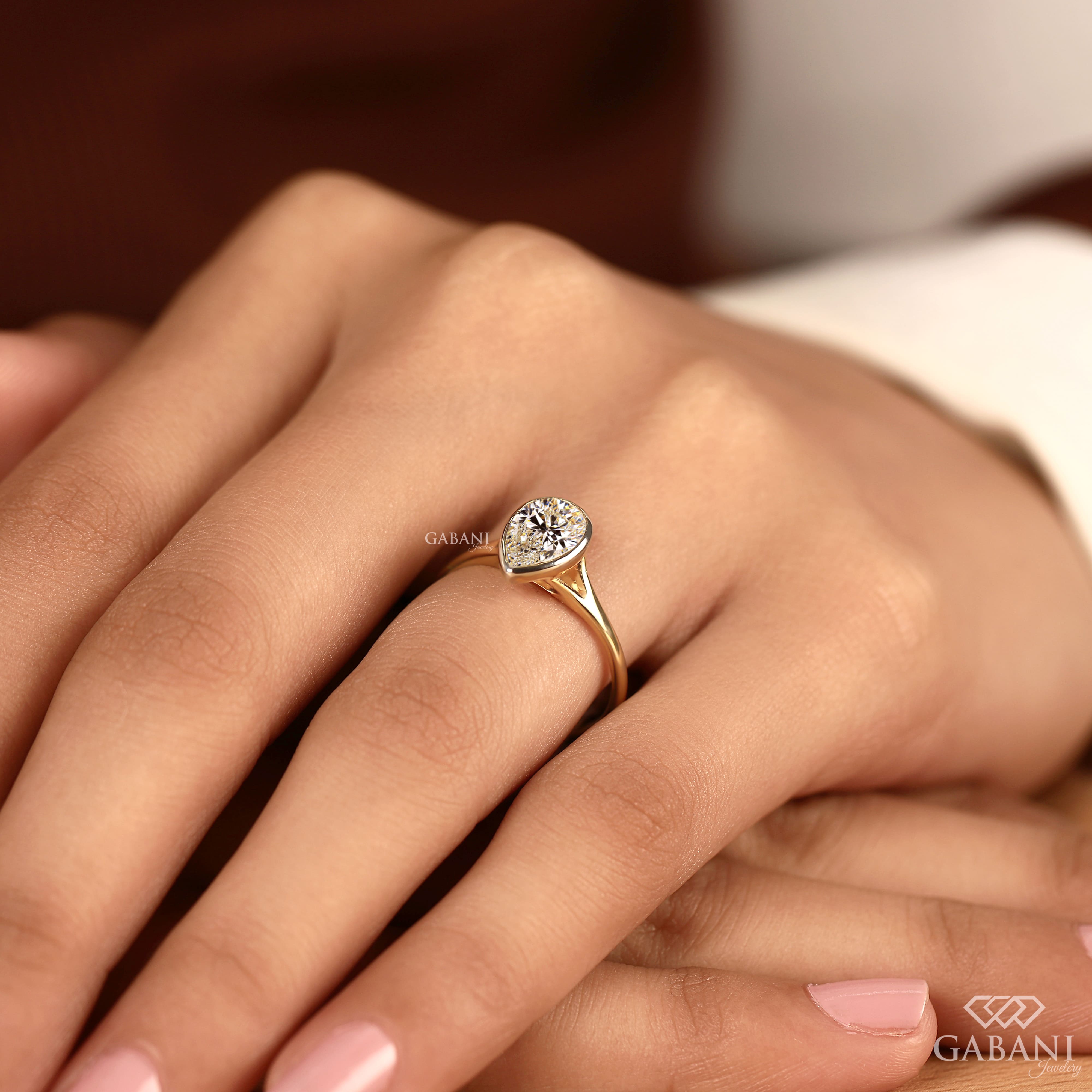 Pear cut diamond solitaire engagement ring with full bezel setting in polished yellow gold