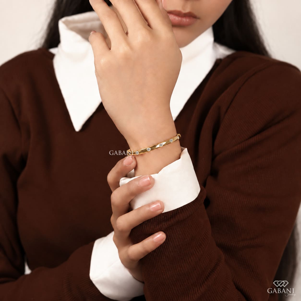 Yellow gold hinged bangle bracelet featuring five round cut diamonds in polished bezel settings along a sleek band.