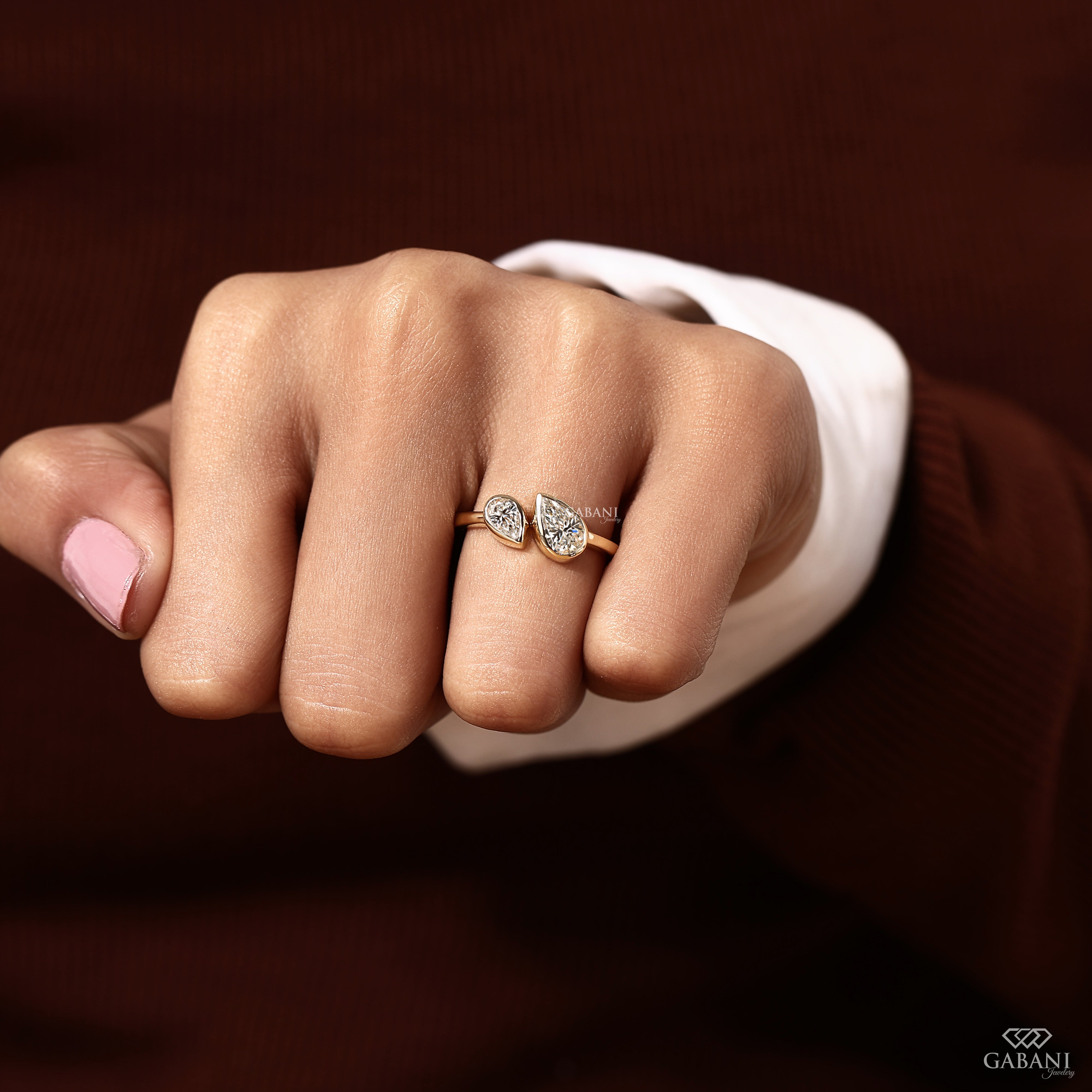 Model wearing a pear cut lab grown diamond bezel set engagement ring with a modern two stone Toi et Moi design