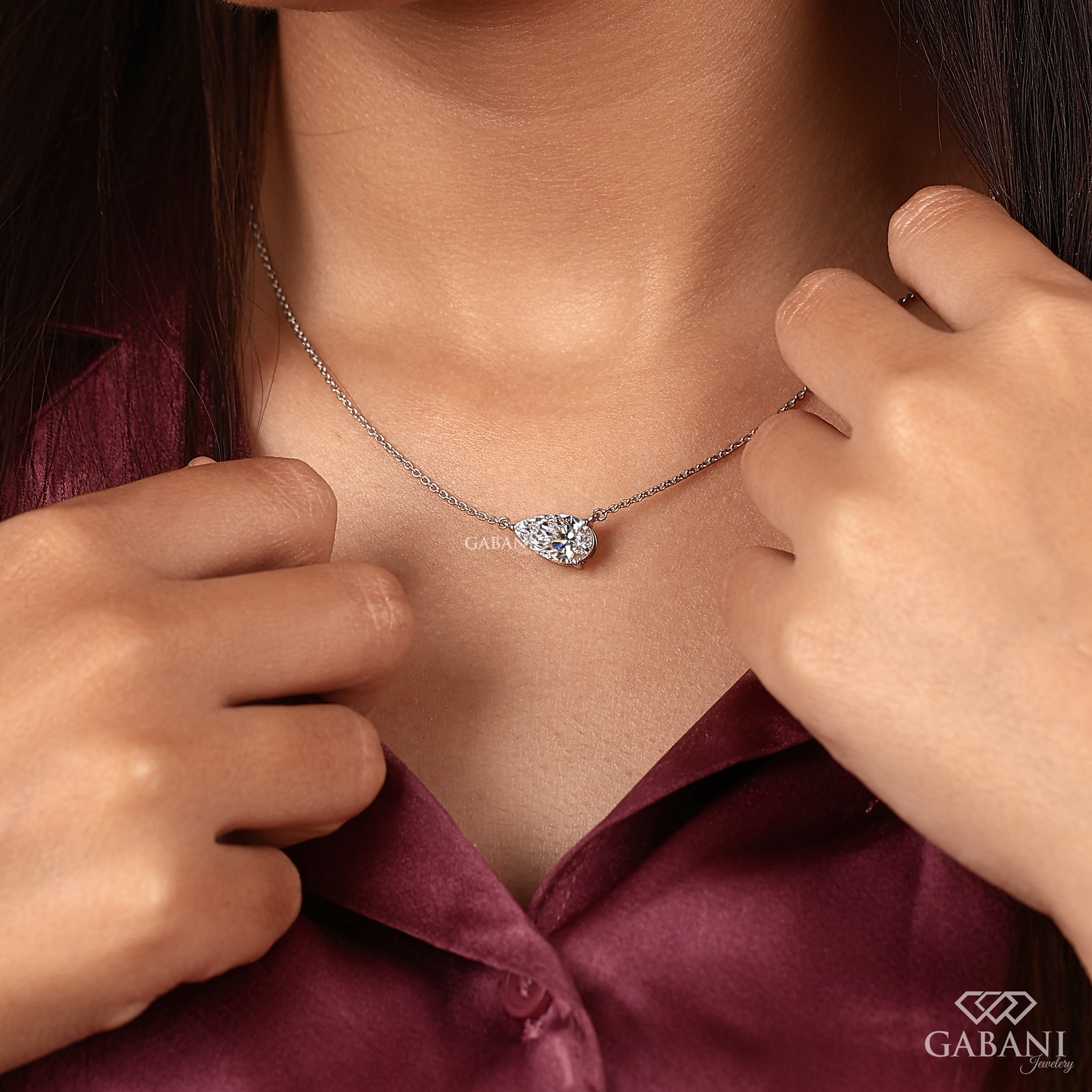 Woman wearing a silver necklace with a heart-shaped pendant, close-up on neck and chest area.