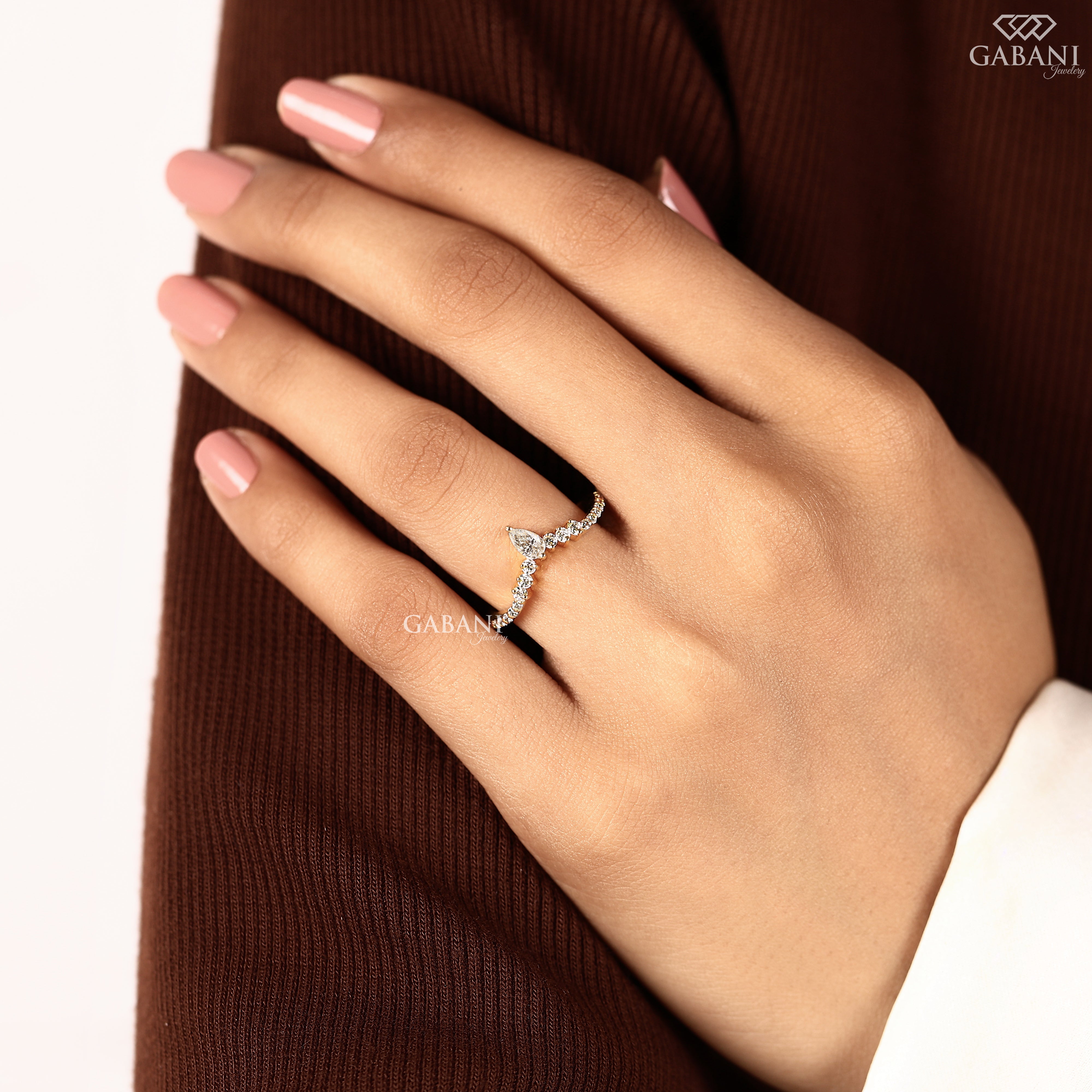 Gabani Jewelry pear cut lab grown diamond V shaped wedding band worn on an engagement finger