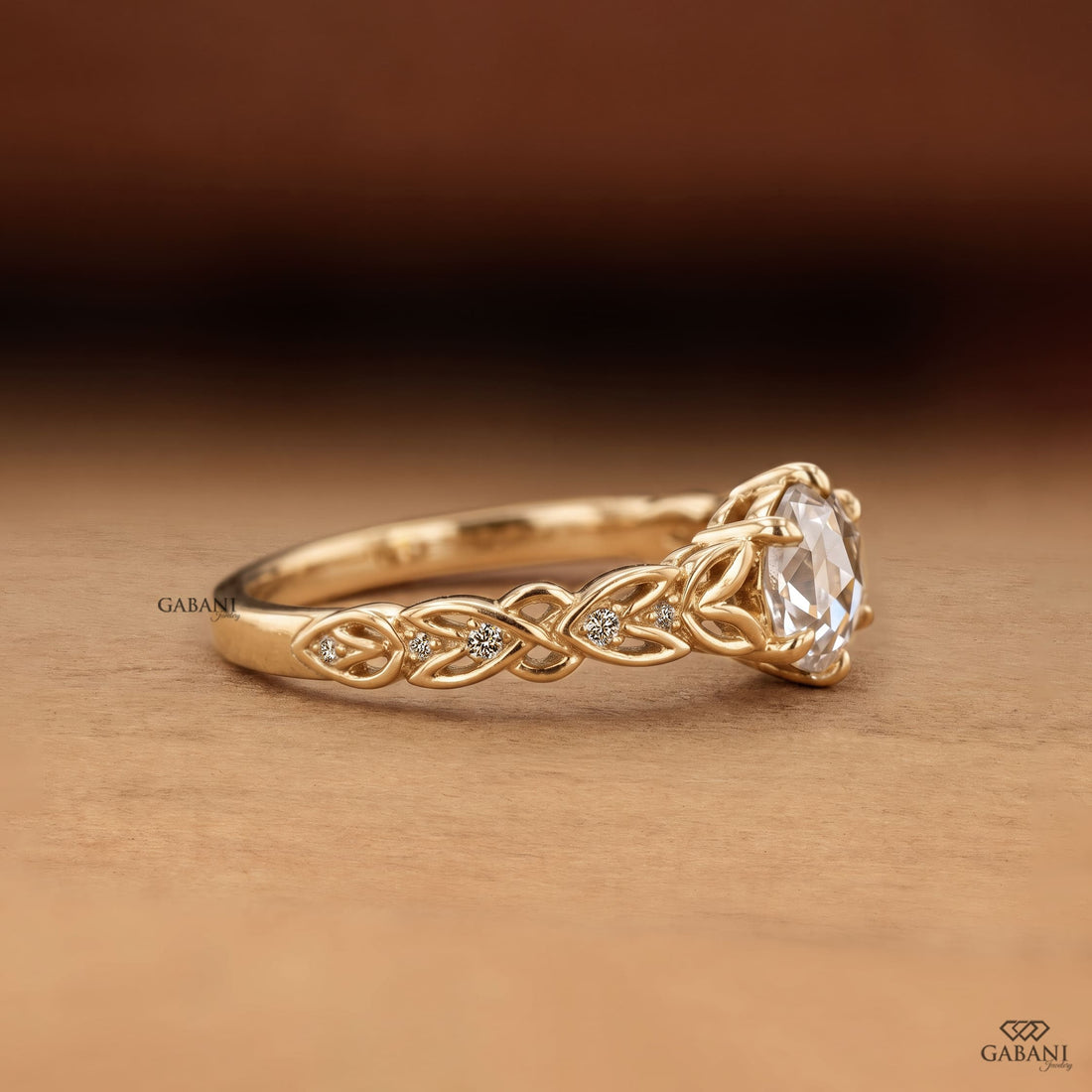 Oval rose cut lab grown diamond engagement ring with leaf vine band, round diamond accents, and six claw prong setting in 14K yellow gold.