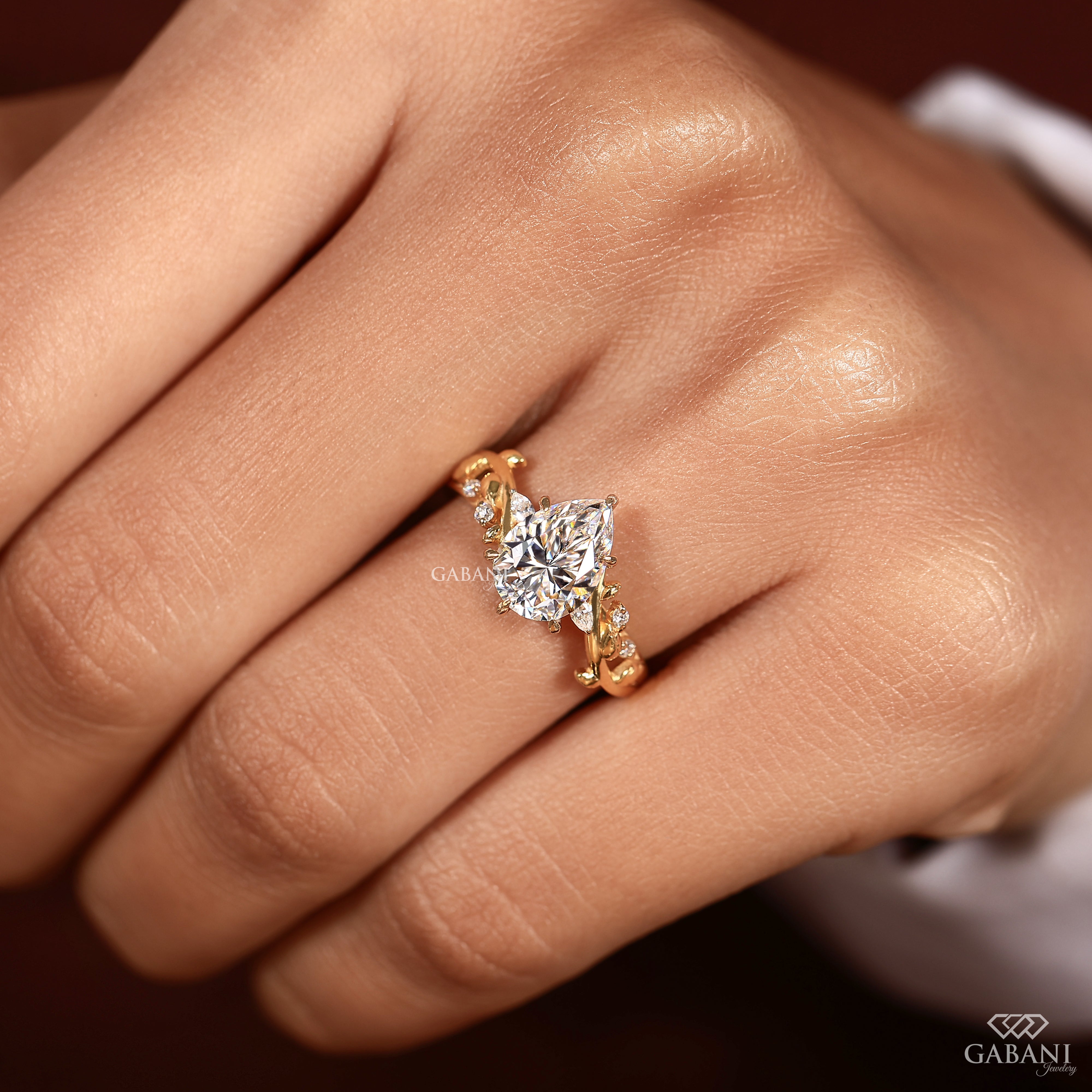 Pear cut lab grown diamond proposal ring worn on engagement finger