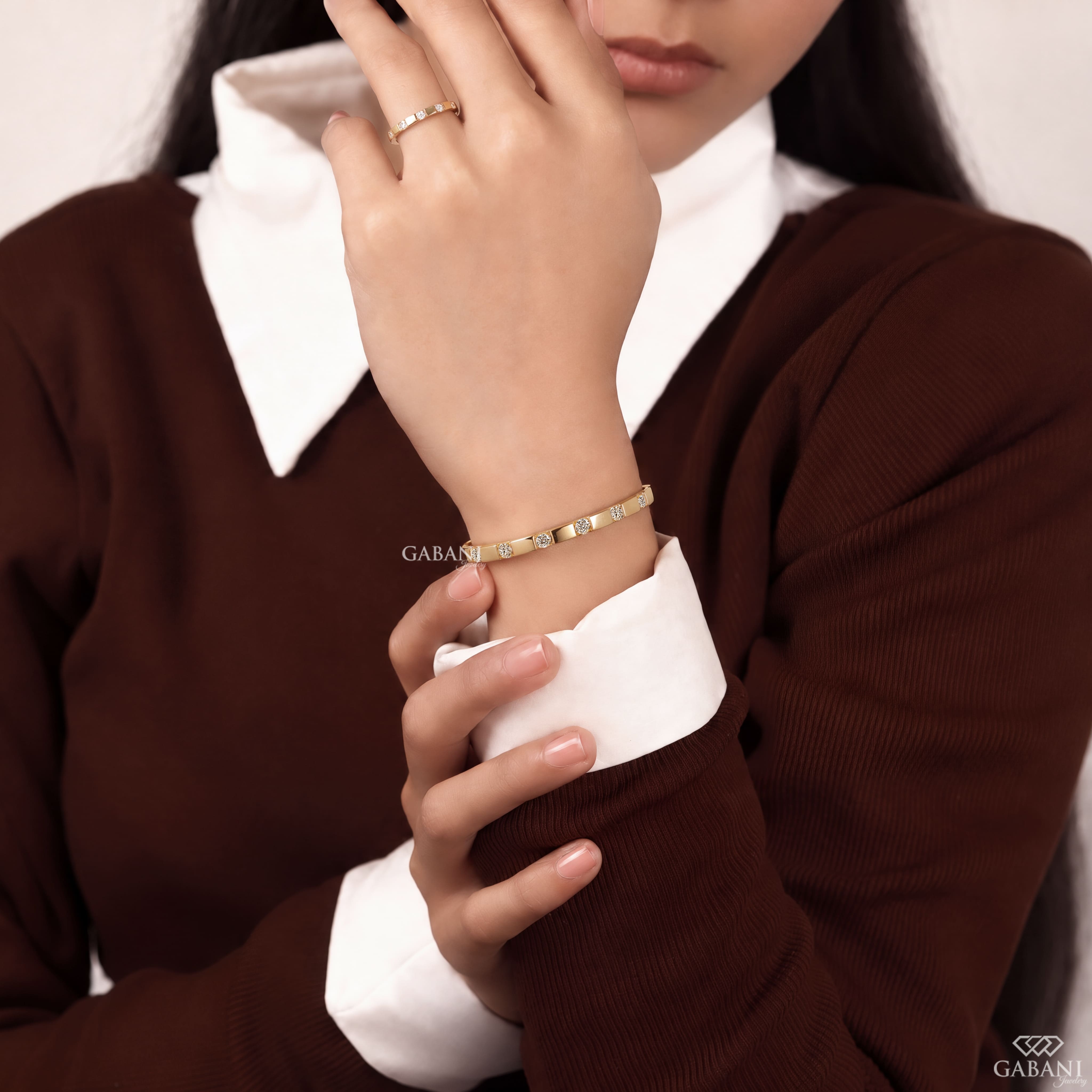 a round lab grown diamond bangle bracelet in yellow gold, featuring evenly spaced sparkling diamonds between polished gold bars in a modern geometric design by Gabani Jewelry.
