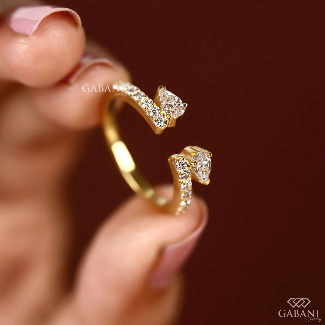 pear cut lab grown diamond open cuff ring showing the partial bezel settings, open ends and polished yellow gold band.