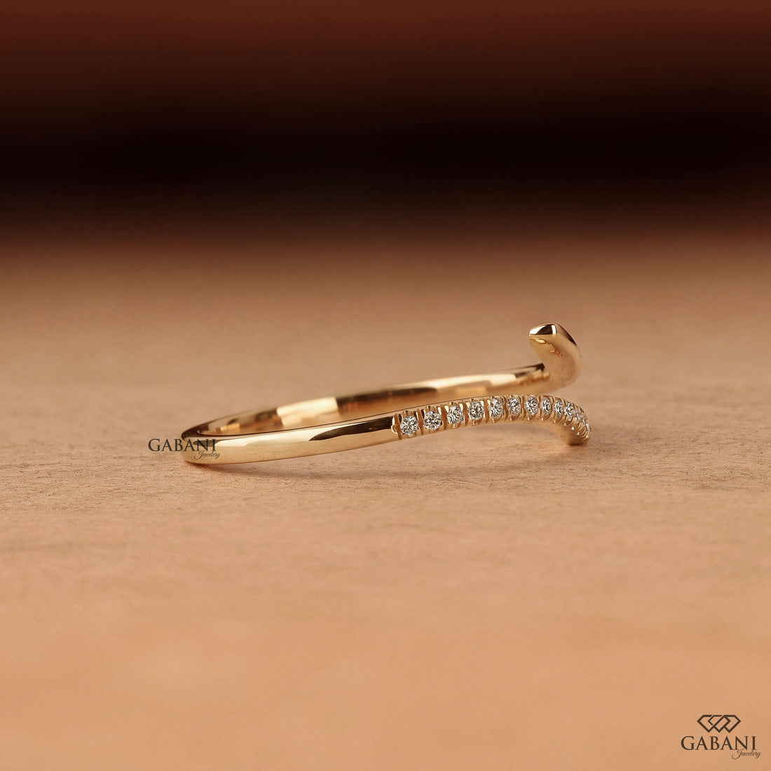 a round lab grown diamond open cuff bangle bracelet in 14K yellow gold, featuring sparkling round diamonds along one curved end and a smooth polished gold wrap design by Gabani Jewelry.