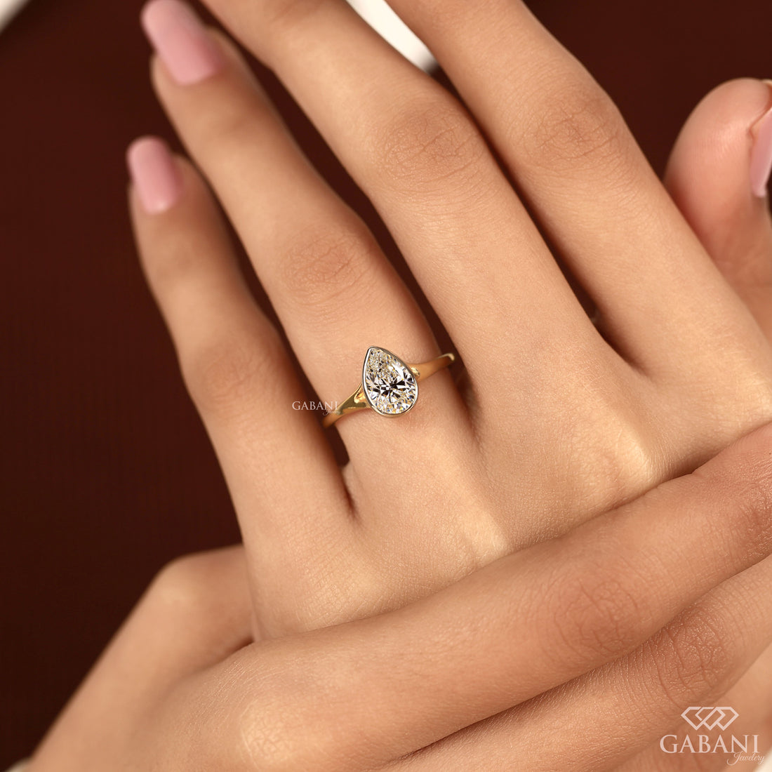 Pear cut diamond solitaire engagement ring with full bezel setting in polished yellow gold