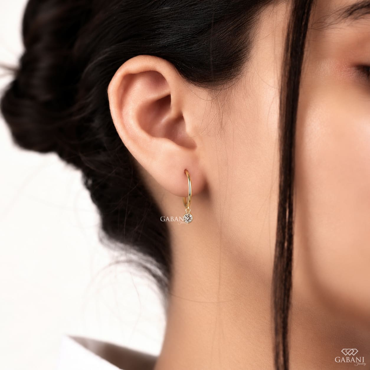 Round lab grown diamond bezel drop huggie earrings in yellow gold with 5 mm diamonds and hinged hoop closure.