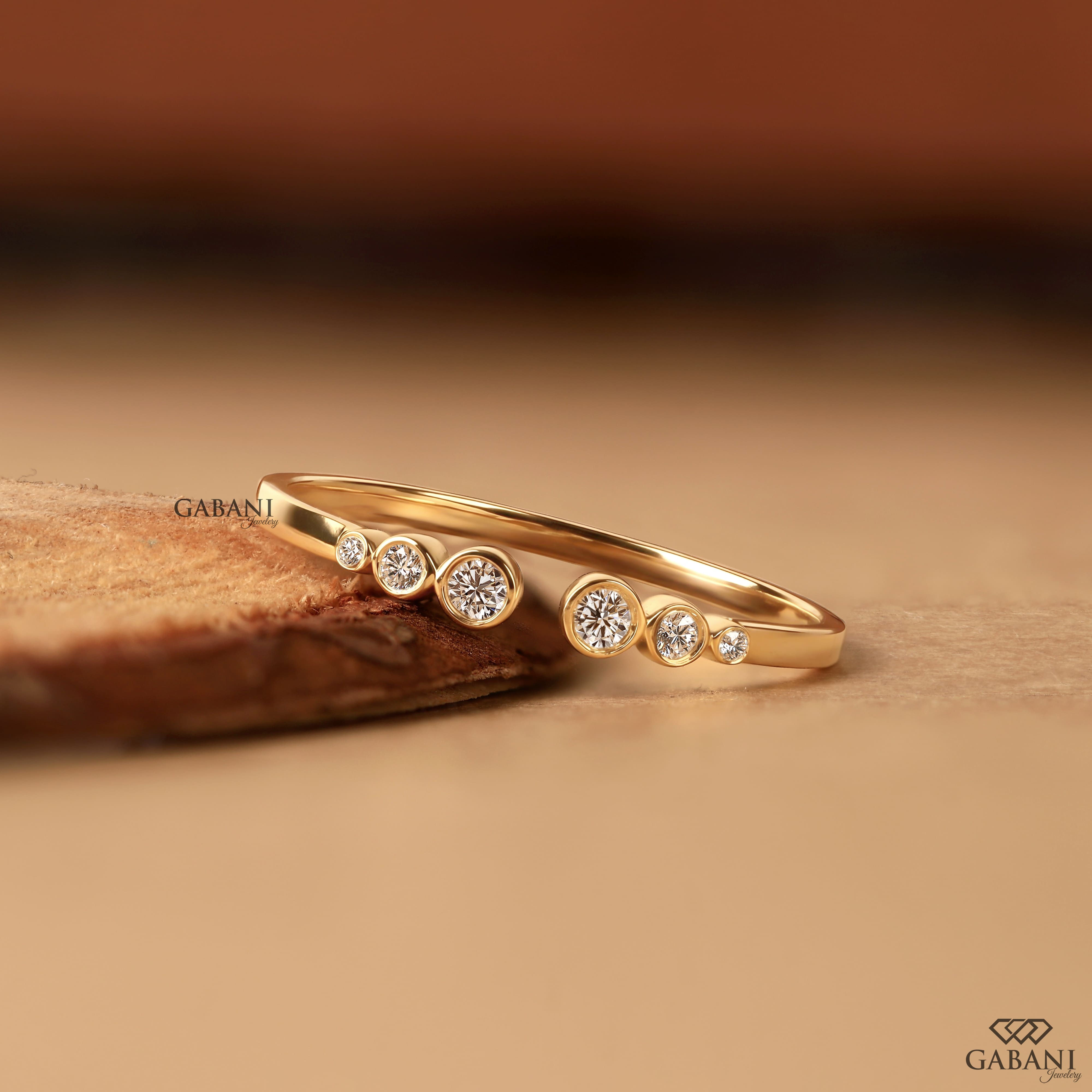a round cut lab grown diamond open cuff band featuring six graduated bezel set diamonds in polished 14K yellow gold, a modern minimalist diamond wedding band by Gabani Jewelry.