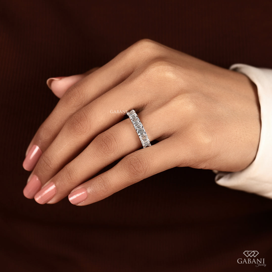 Hand model wearing an emerald cut lab grown diamond half eternity band with a clean and elegant bridal look
