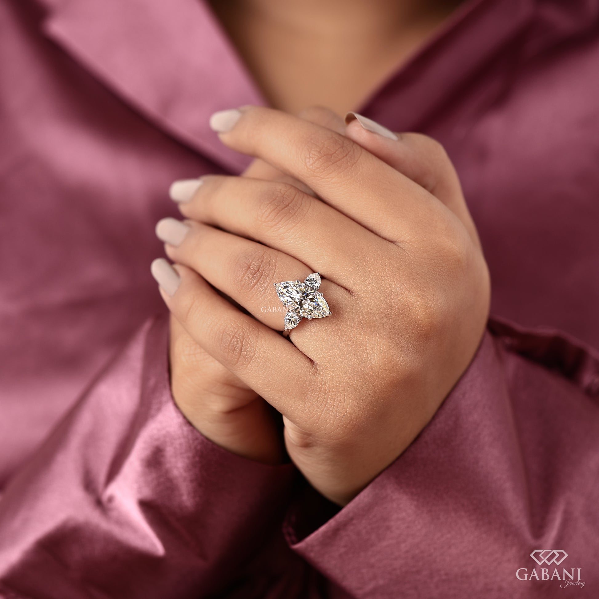 Prong set marquise cut lab diamond with pear side stones in an elegant three stone engagement ring