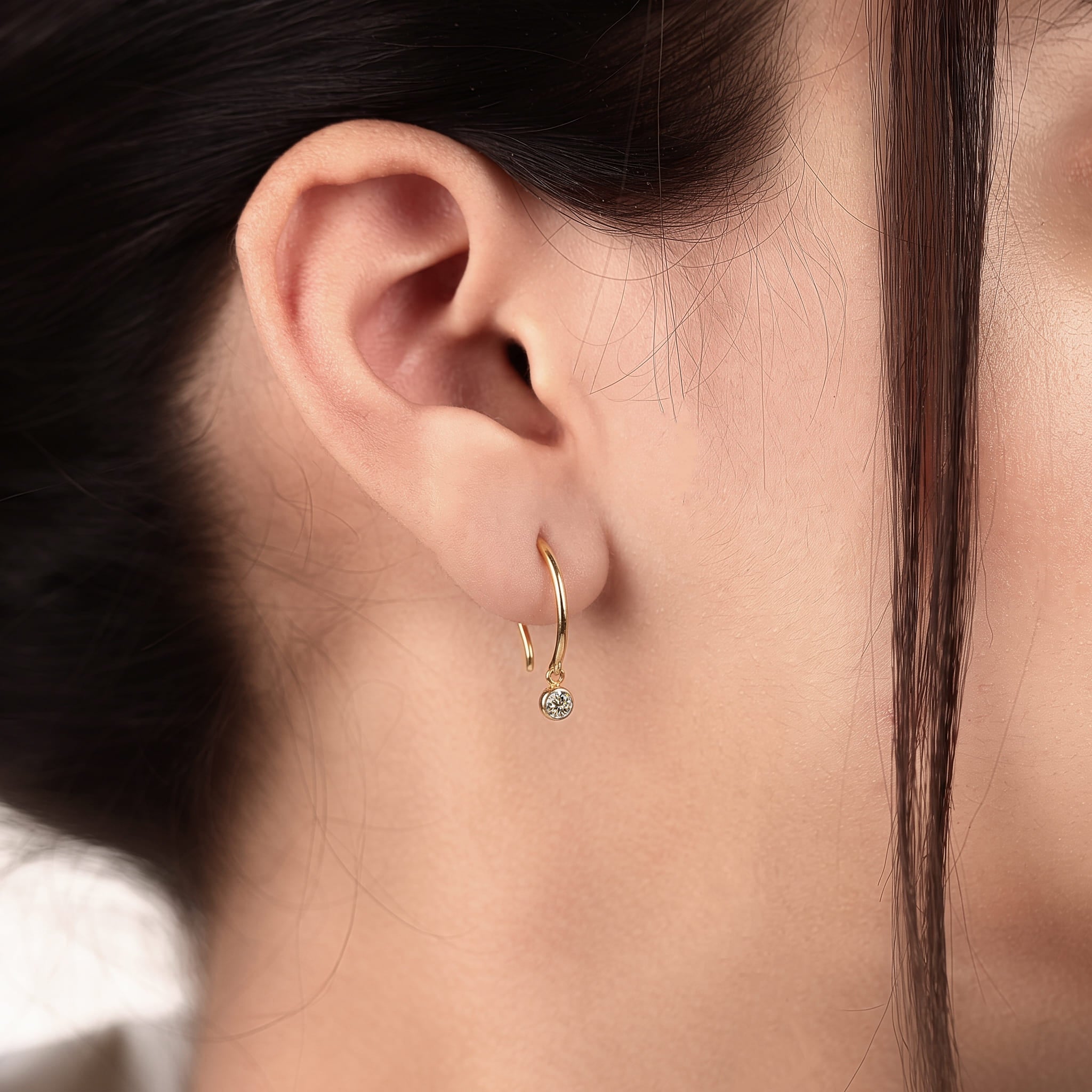 Round cut lab grown diamond hook earrings with 0.10 CTW, bezel set stones and a slim curved gold drop design for everyday wear.