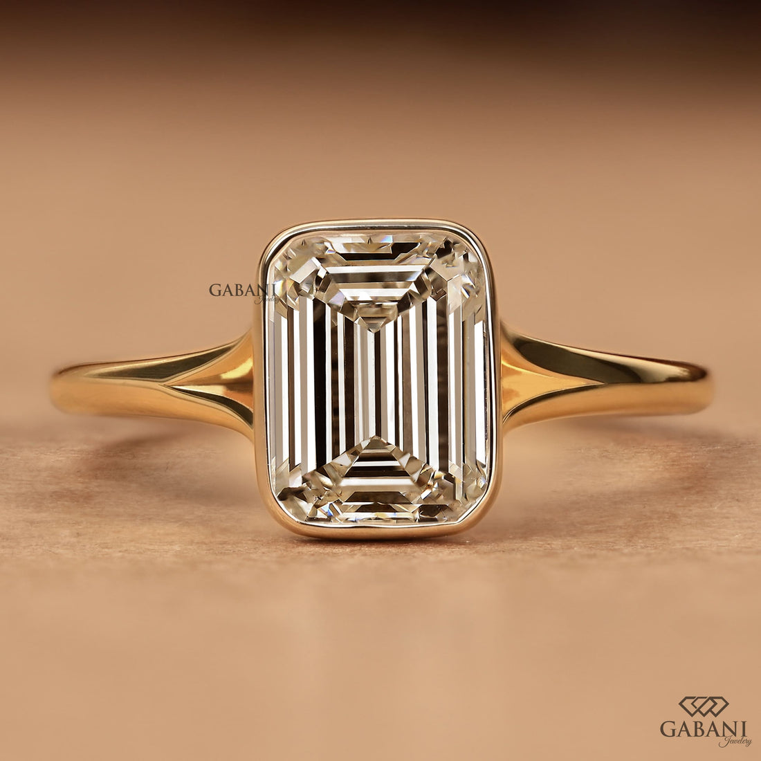 Front view of emerald cut diamond solitaire engagement ring with full bezel setting in yellow gold