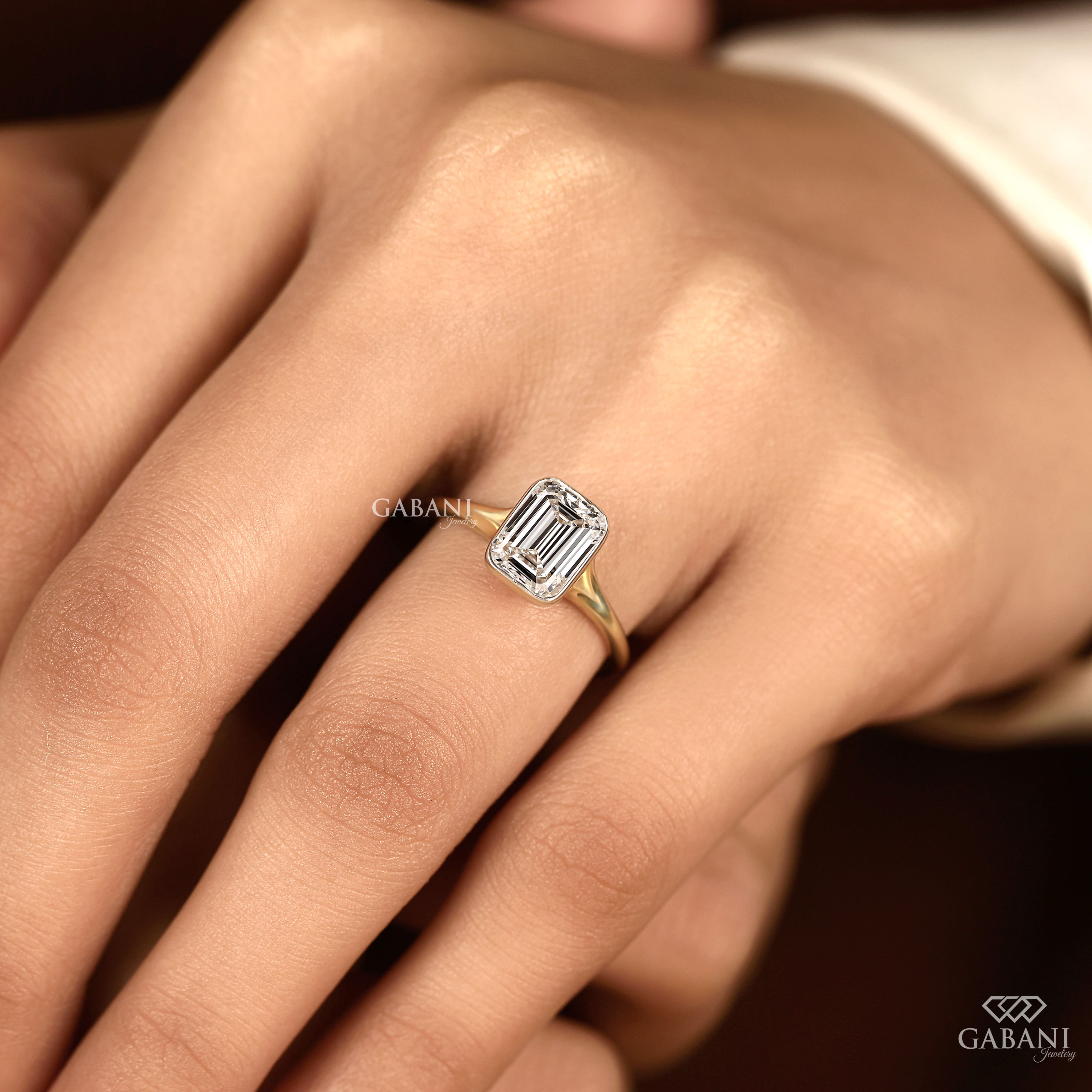 emerald cut diamond solitaire engagement ring with full bezel setting in yellow gold