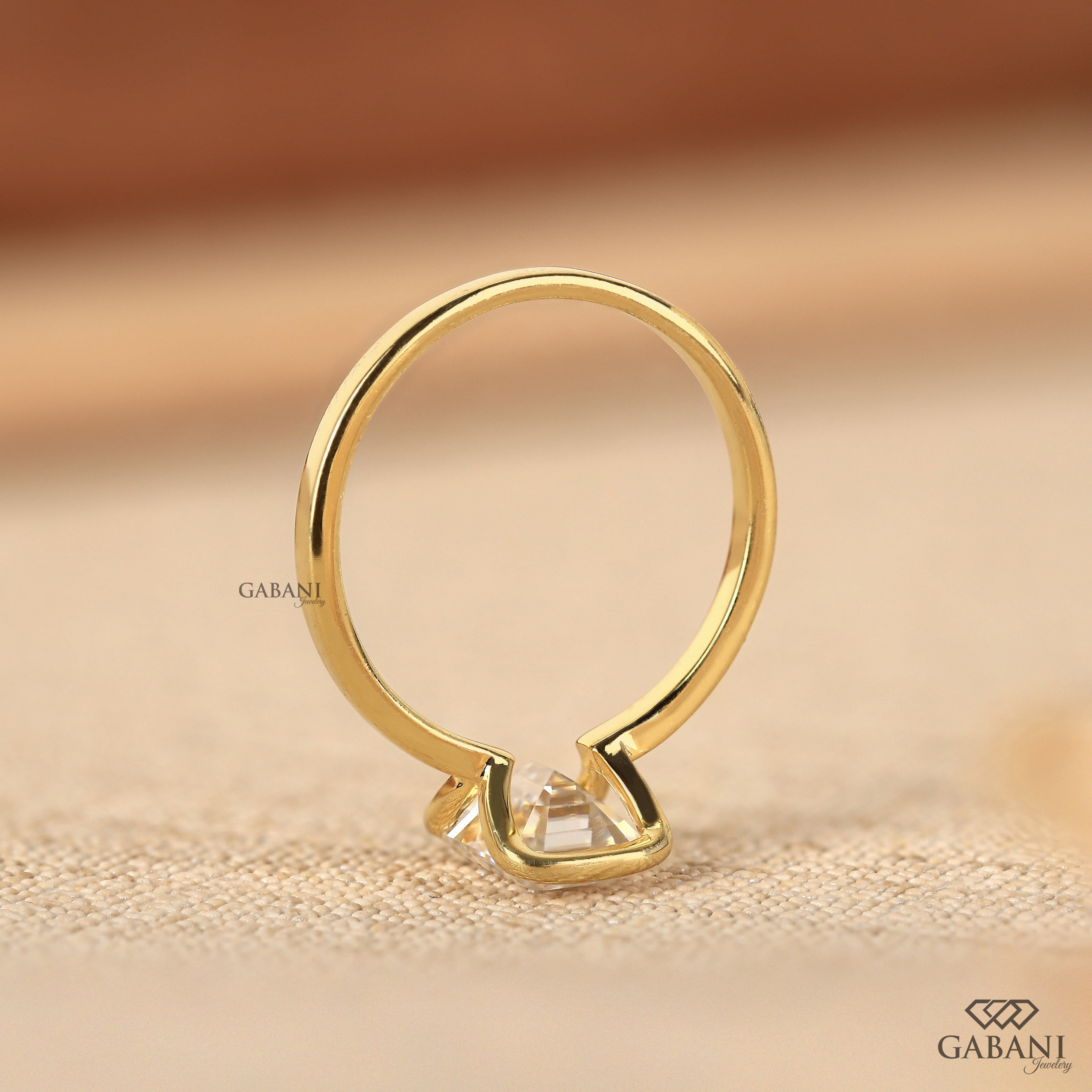 Front view of emerald cut lab grown diamond solitaire engagement ring with modern half bezel setting and polished 14K yellow gold band.