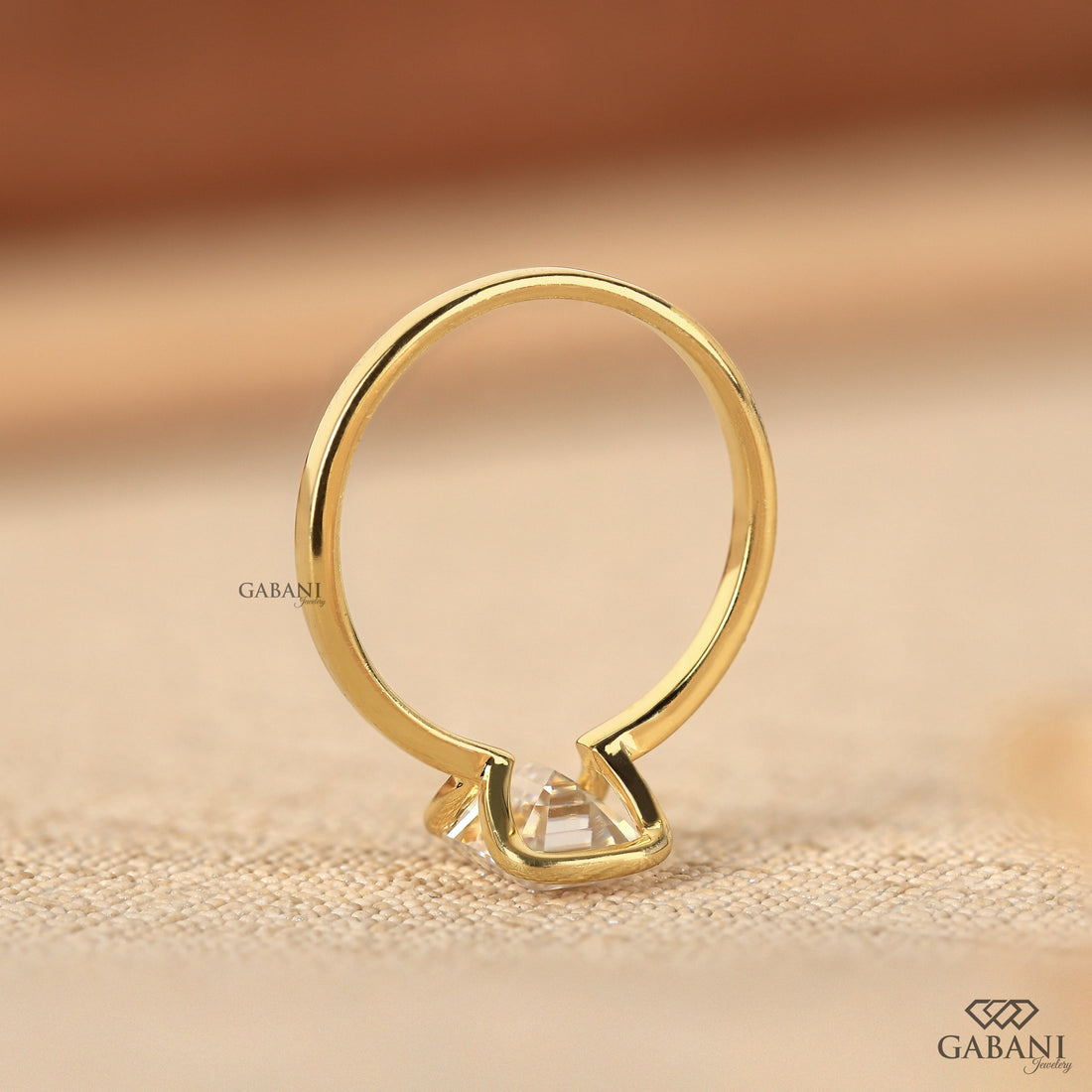 Front view of emerald cut lab grown diamond solitaire engagement ring with modern half bezel setting and polished 14K yellow gold band.