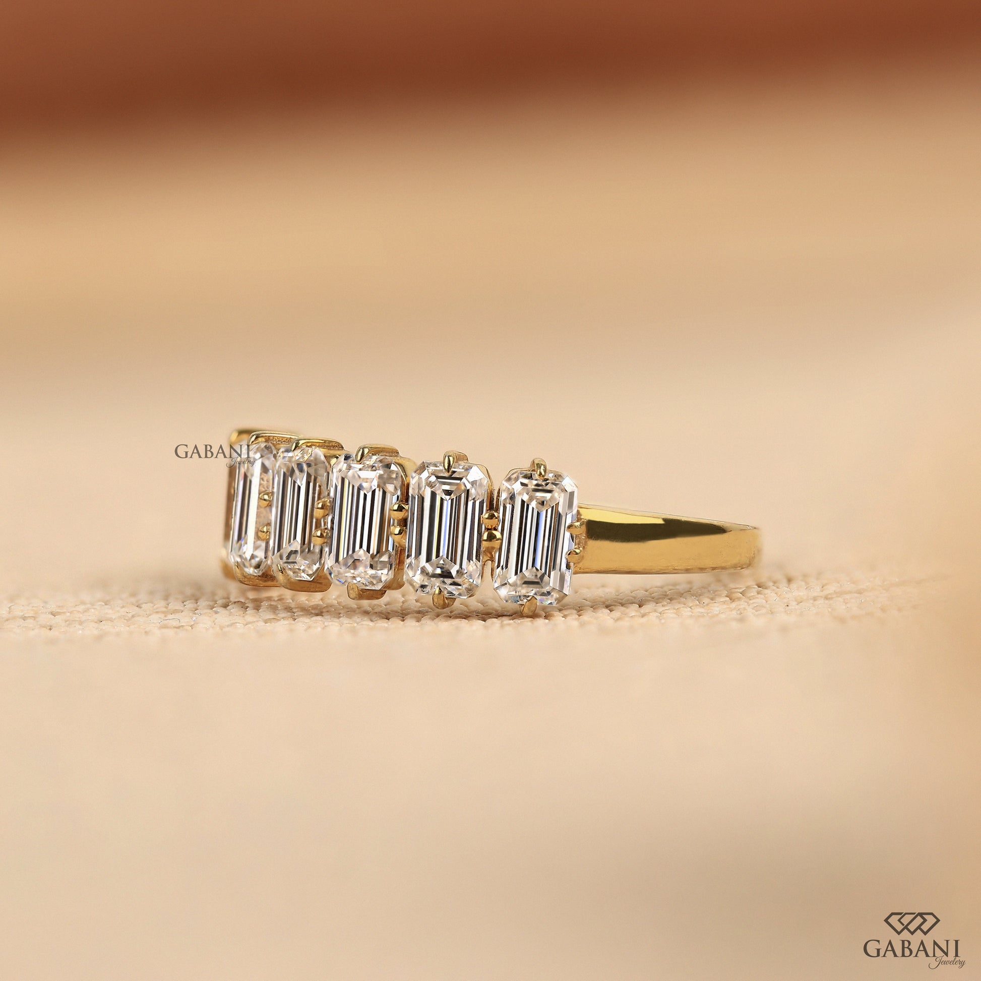 Seven diamond ring with emerald cut lab grown stones set in a refined yellow gold band
