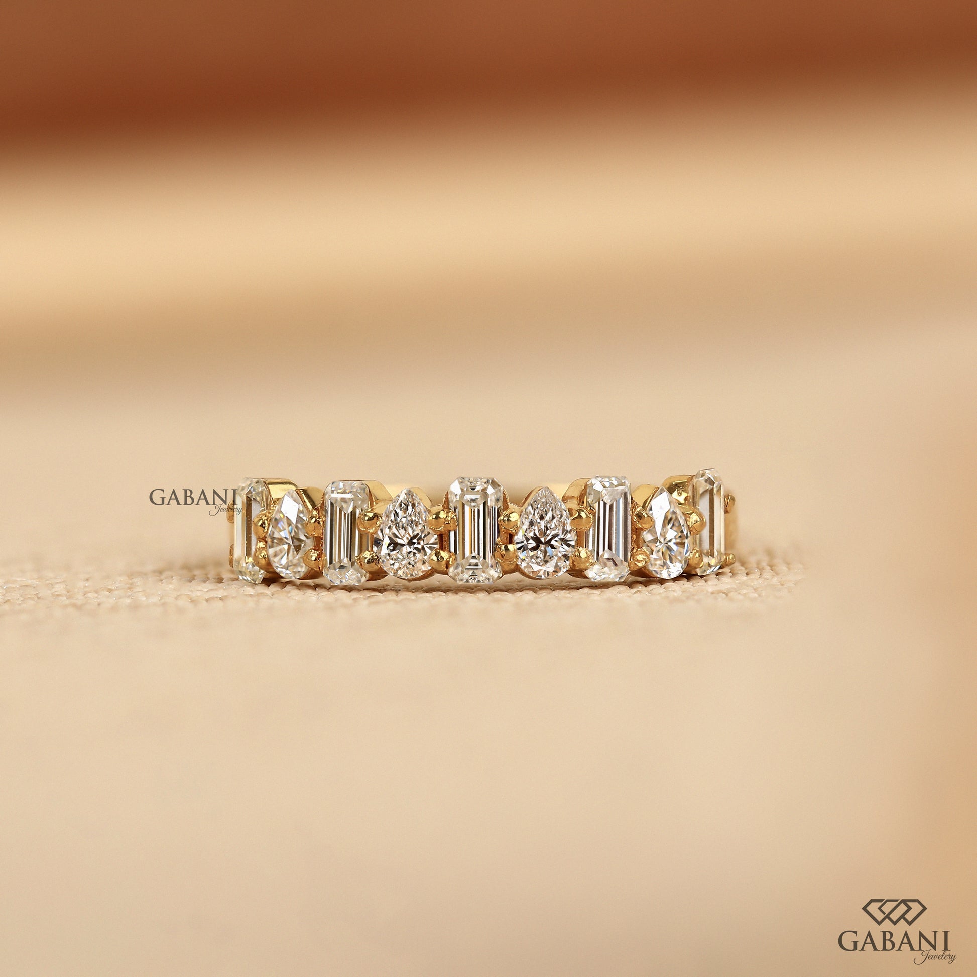 diamond wedding band with emerald and pear cut lab grown diamonds in yellow gold half eternity style