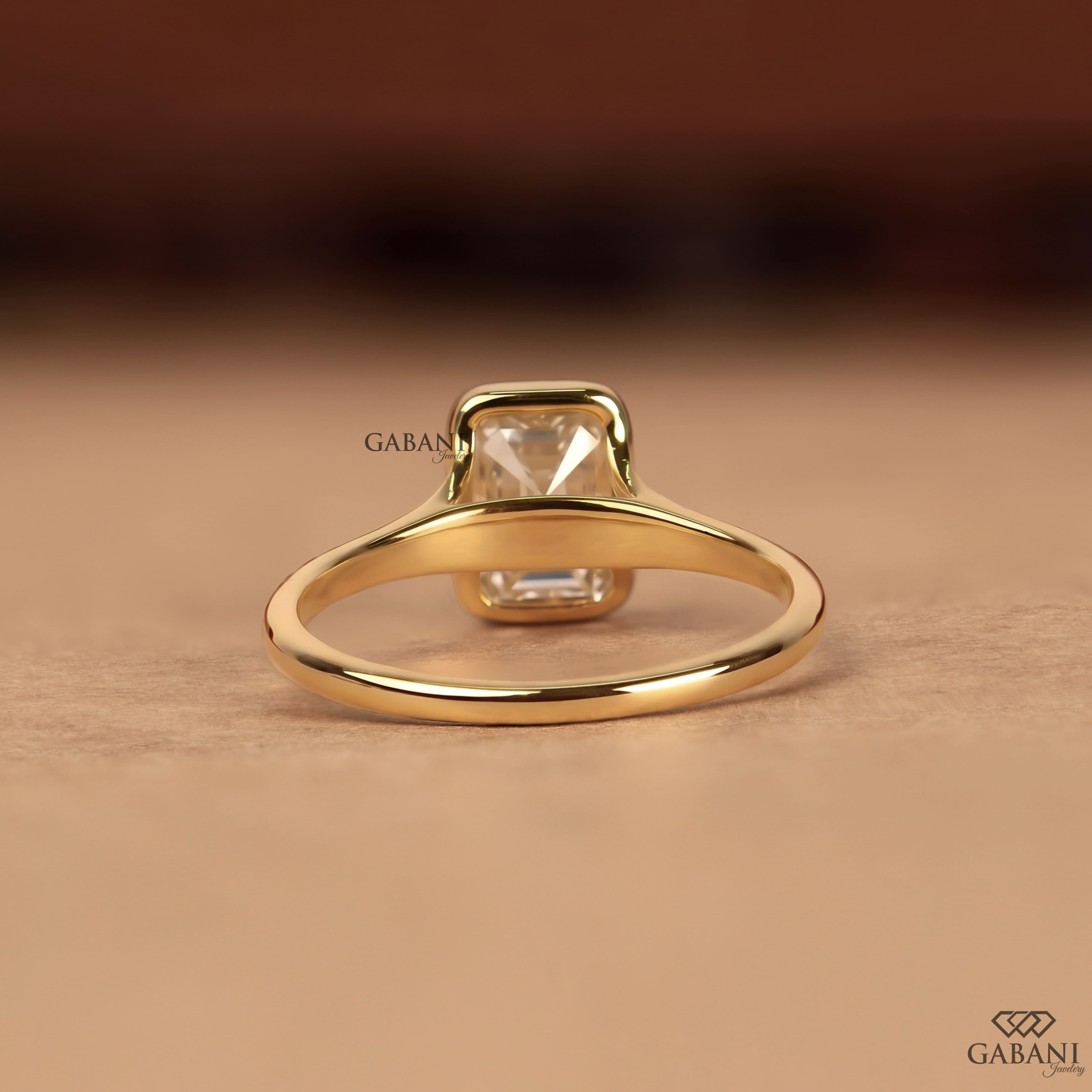 emerald cut diamond solitaire engagement ring with full bezel setting in yellow gold