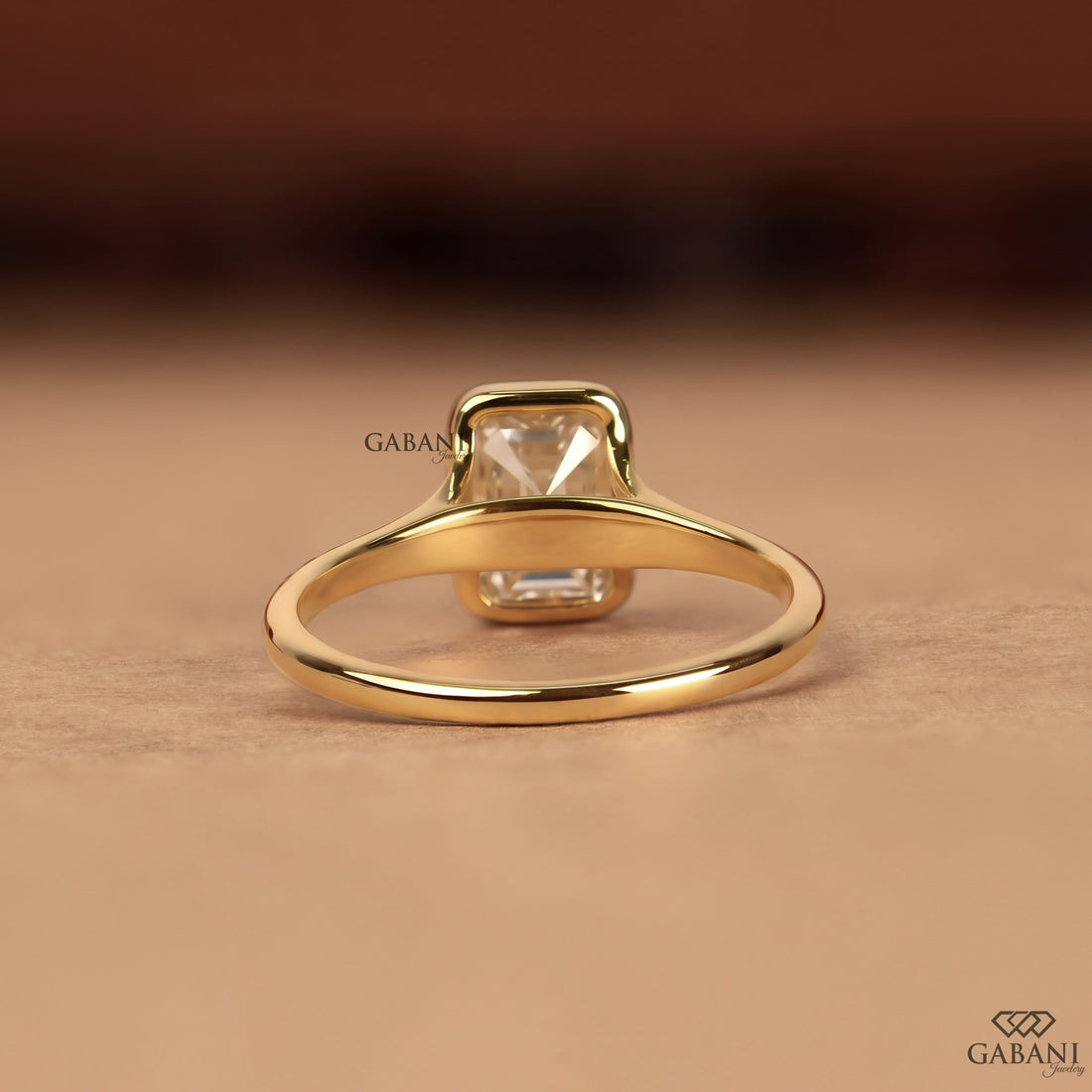 emerald cut diamond solitaire engagement ring with full bezel setting in yellow gold