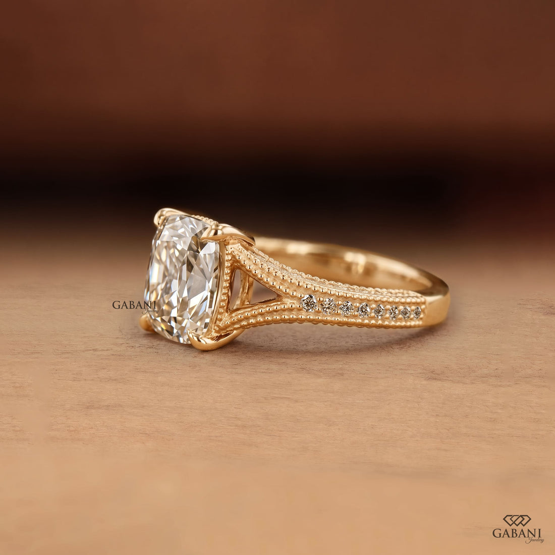 old mine cushion cut lab grown diamond engagement ring with split shank, round diamond accents and milgrain detail in 14K yellow gold.