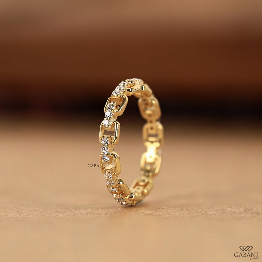 a round lab grown diamond chain link eternity band in 14K yellow gold, featuring prong set diamonds and rectangular gold links.