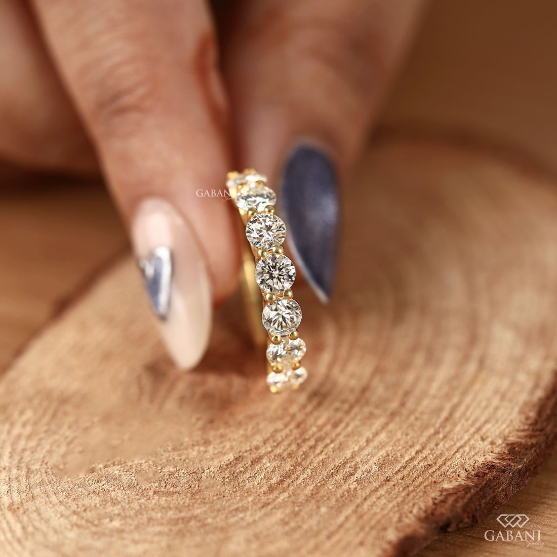 seven round cut lab grown diamonds in a yellow gold half eternity wedding band with open prong settings and a smooth shank.