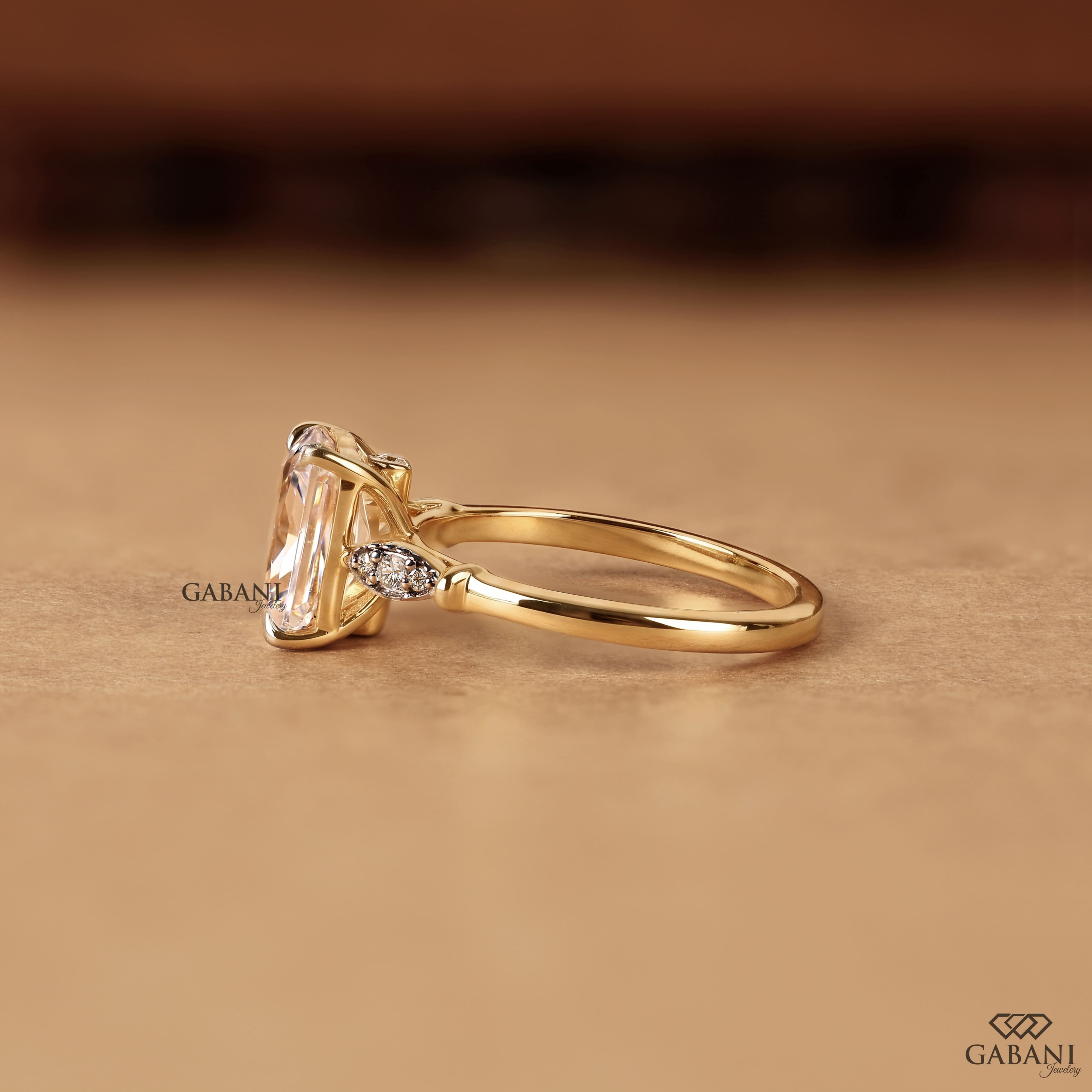 Radiant cut lab grown diamond engagement ring with round side diamond clusters, four prong setting and polished gold band.
