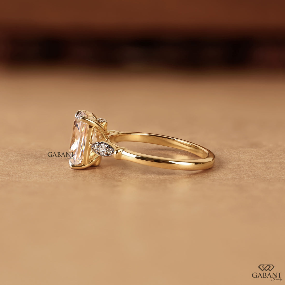 Radiant cut lab grown diamond engagement ring with round side diamond clusters, four prong setting and polished gold band.