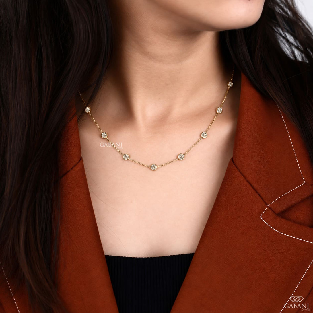 Yellow gold station necklace featuring evenly spaced round cut diamonds in full bezel settings along a delicate gold chain.