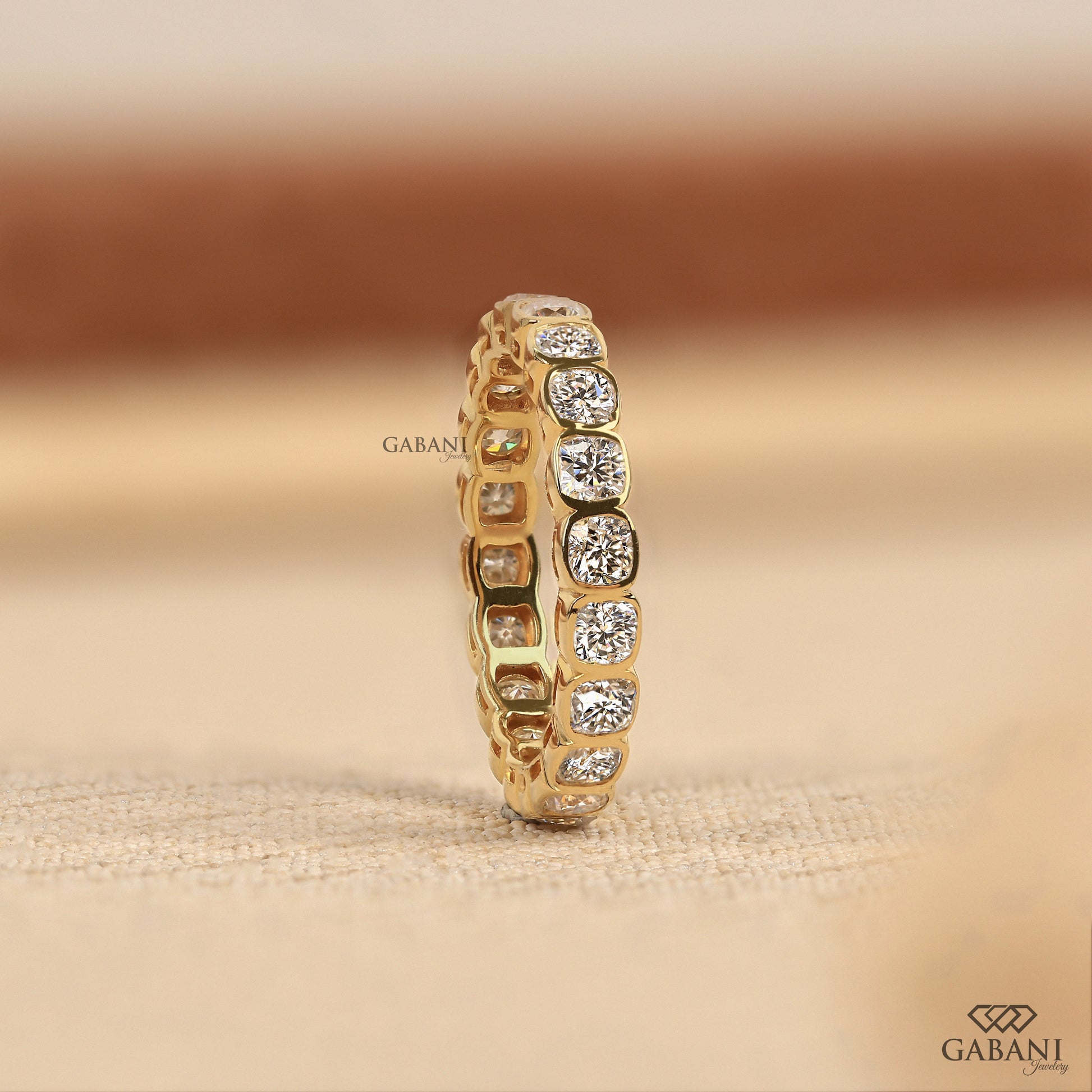 Lab grown diamond eternity band with cushion cut stones and secure bezel setting in polished metal