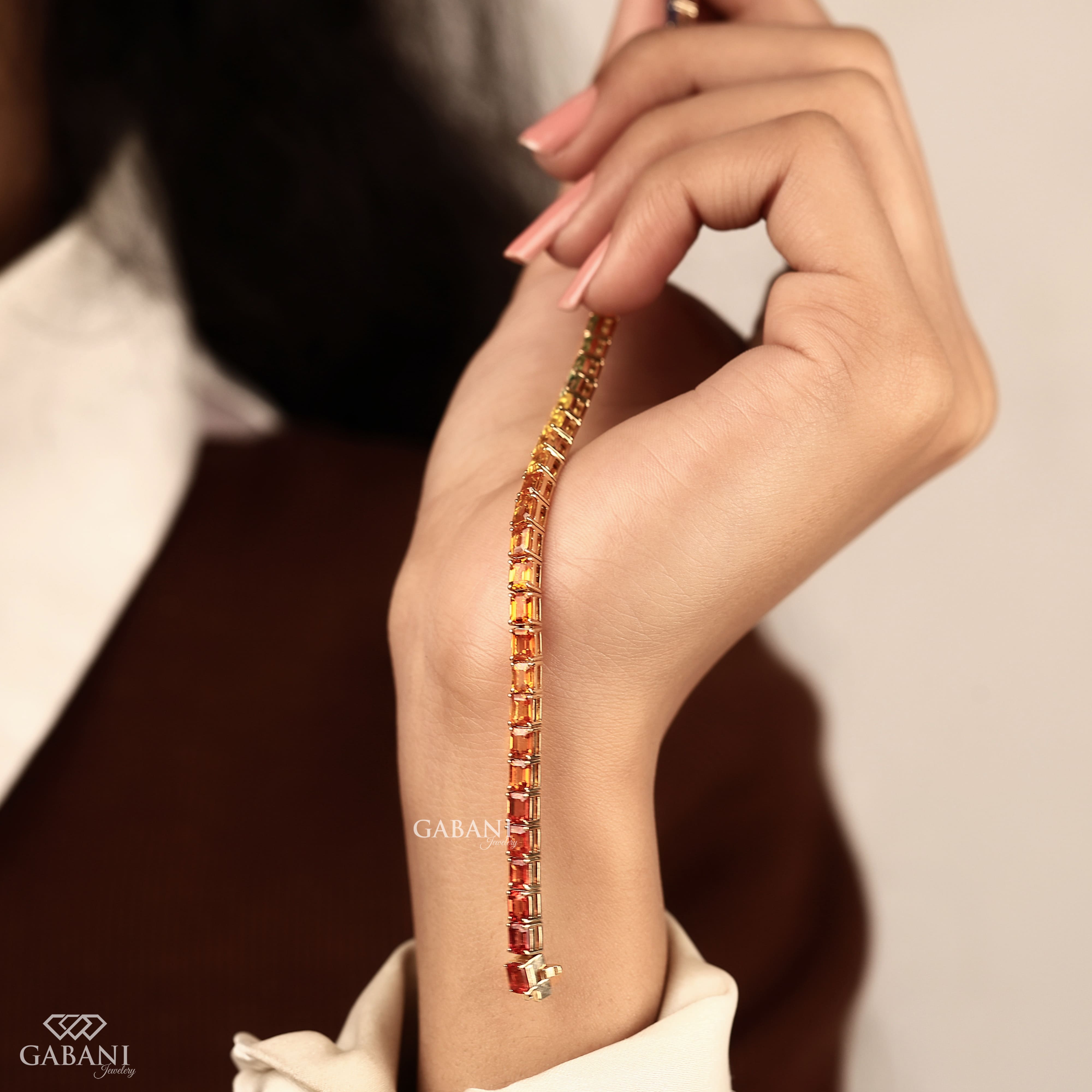 Multicolor emerald cut gemstone tennis bracelet featuring 3×4 mm prong-set stones in orange, yellow, green, blue and red tones with secure box clasp.