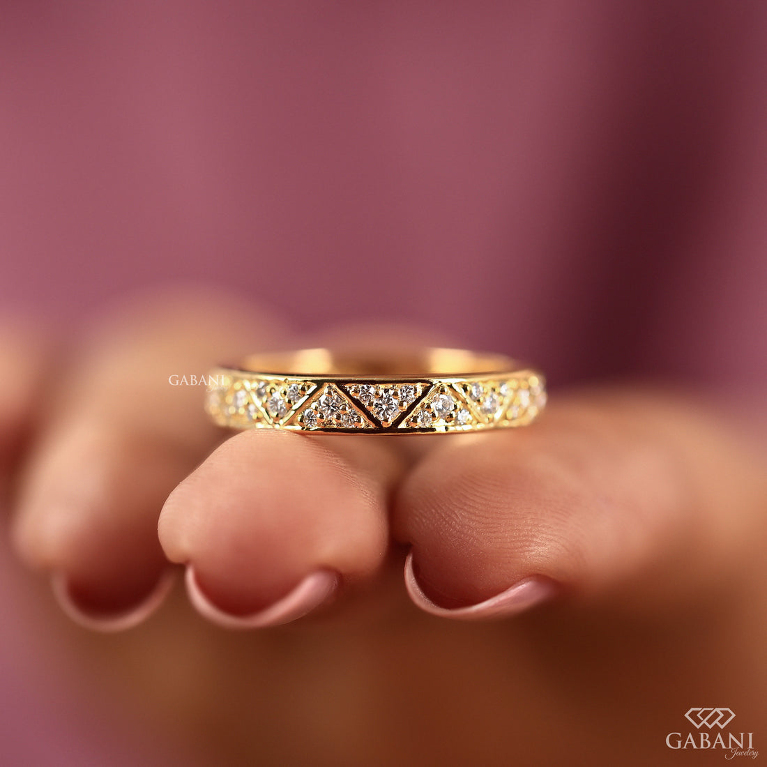 Round lab grown diamond wedding band with geometric triangular pattern and polished yellow gold setting.