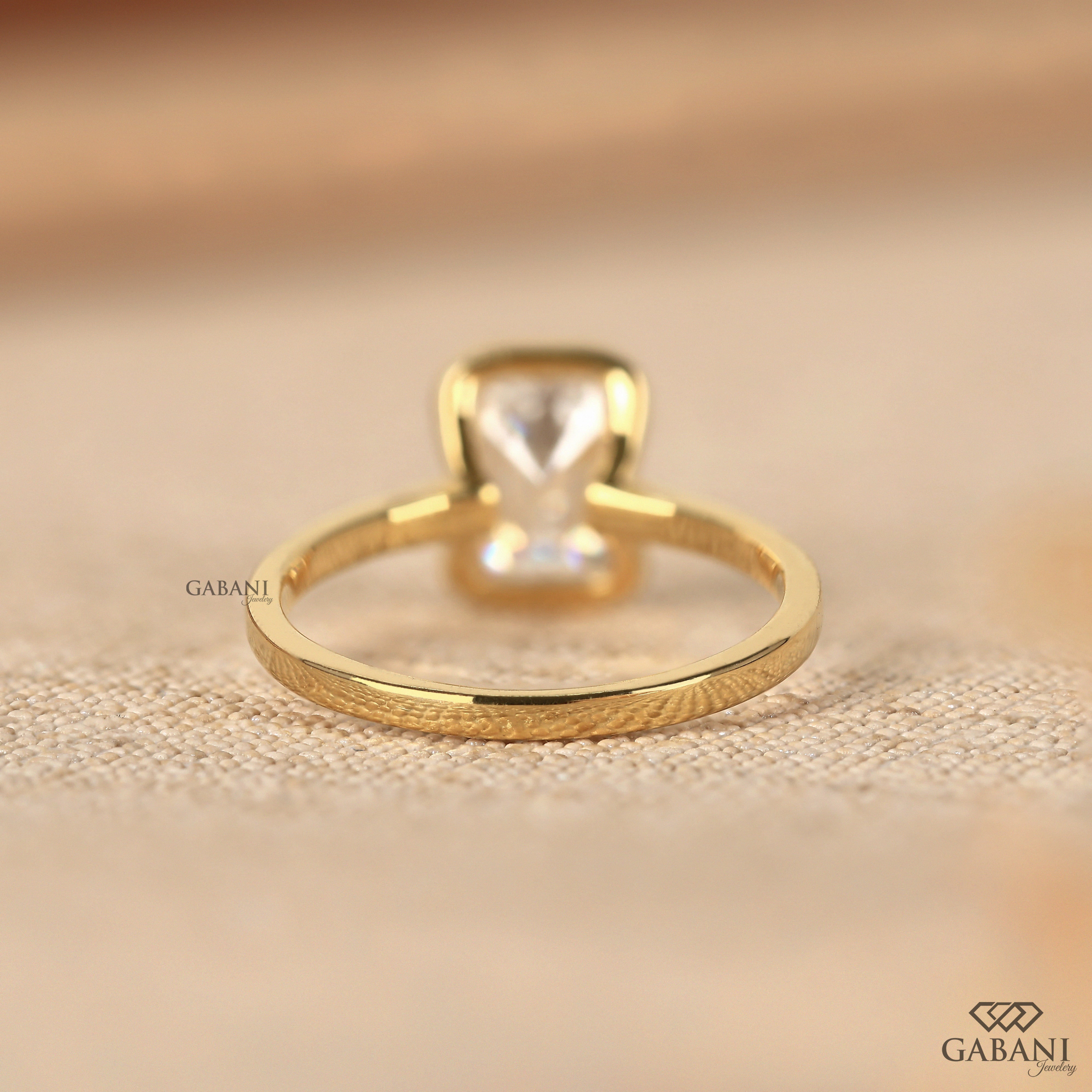 Front view of emerald cut lab grown diamond solitaire engagement ring with modern half bezel setting and polished 14K yellow gold band.