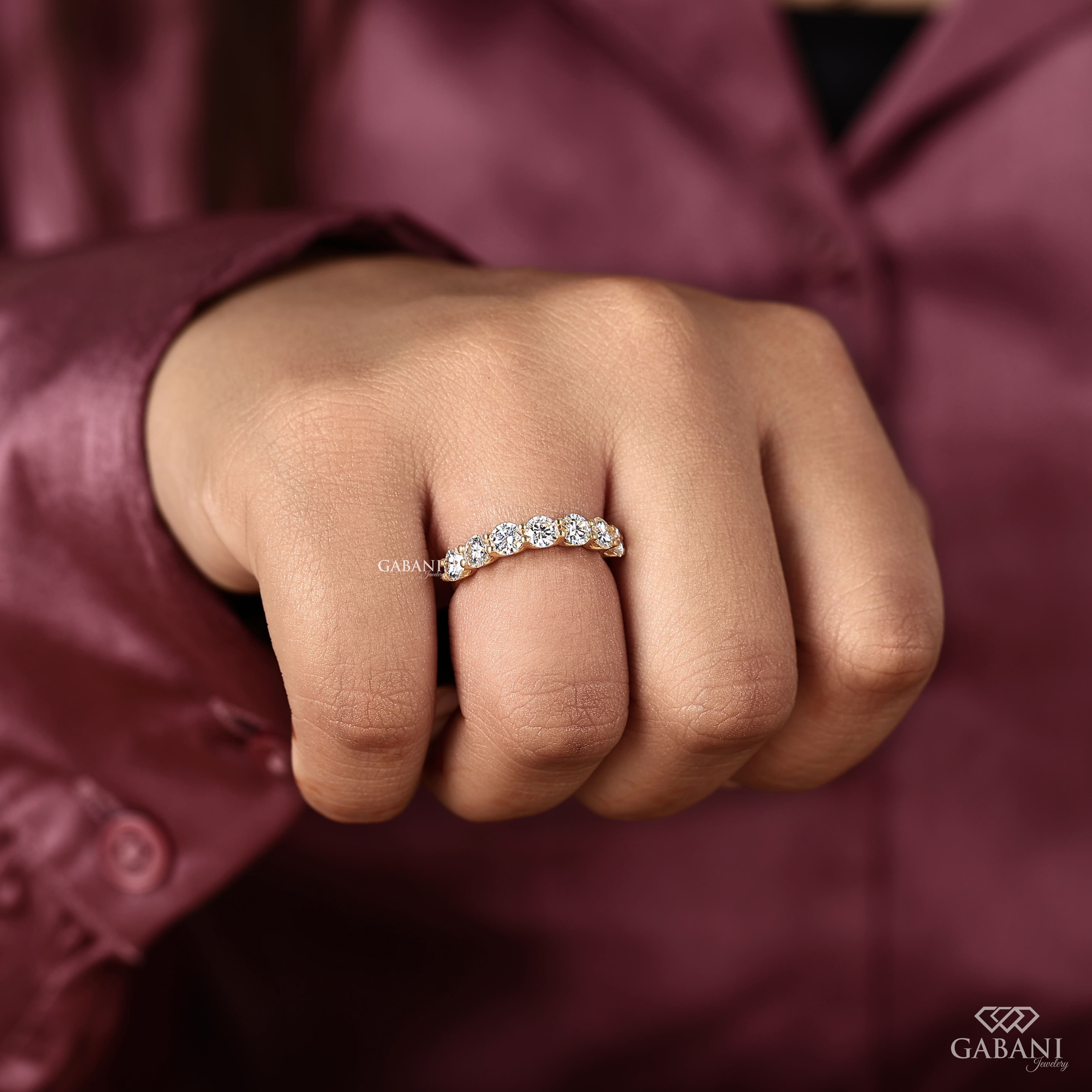seven round cut lab grown diamonds in a yellow gold half eternity wedding band with open prong settings and a smooth shank.