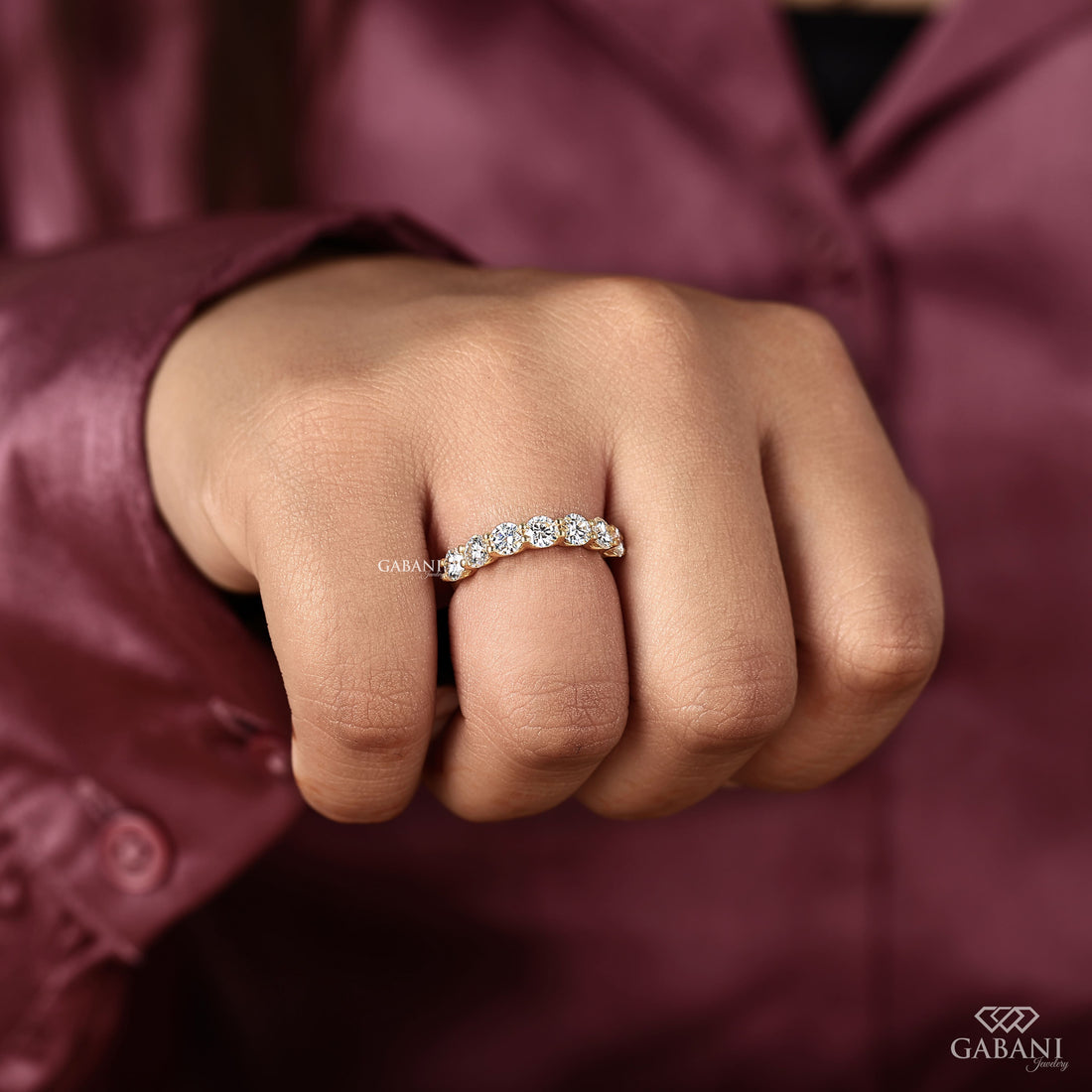 seven round cut lab grown diamonds in a yellow gold half eternity wedding band with open prong settings and a smooth shank.