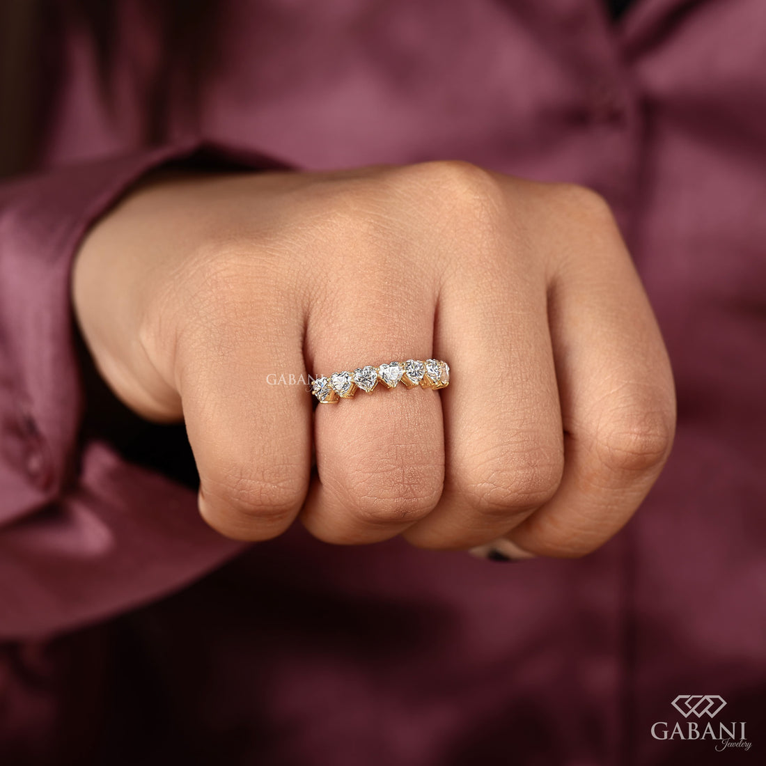 seven heart cut lab grown diamonds in a yellow gold half eternity wedding band with delicate prong settings.