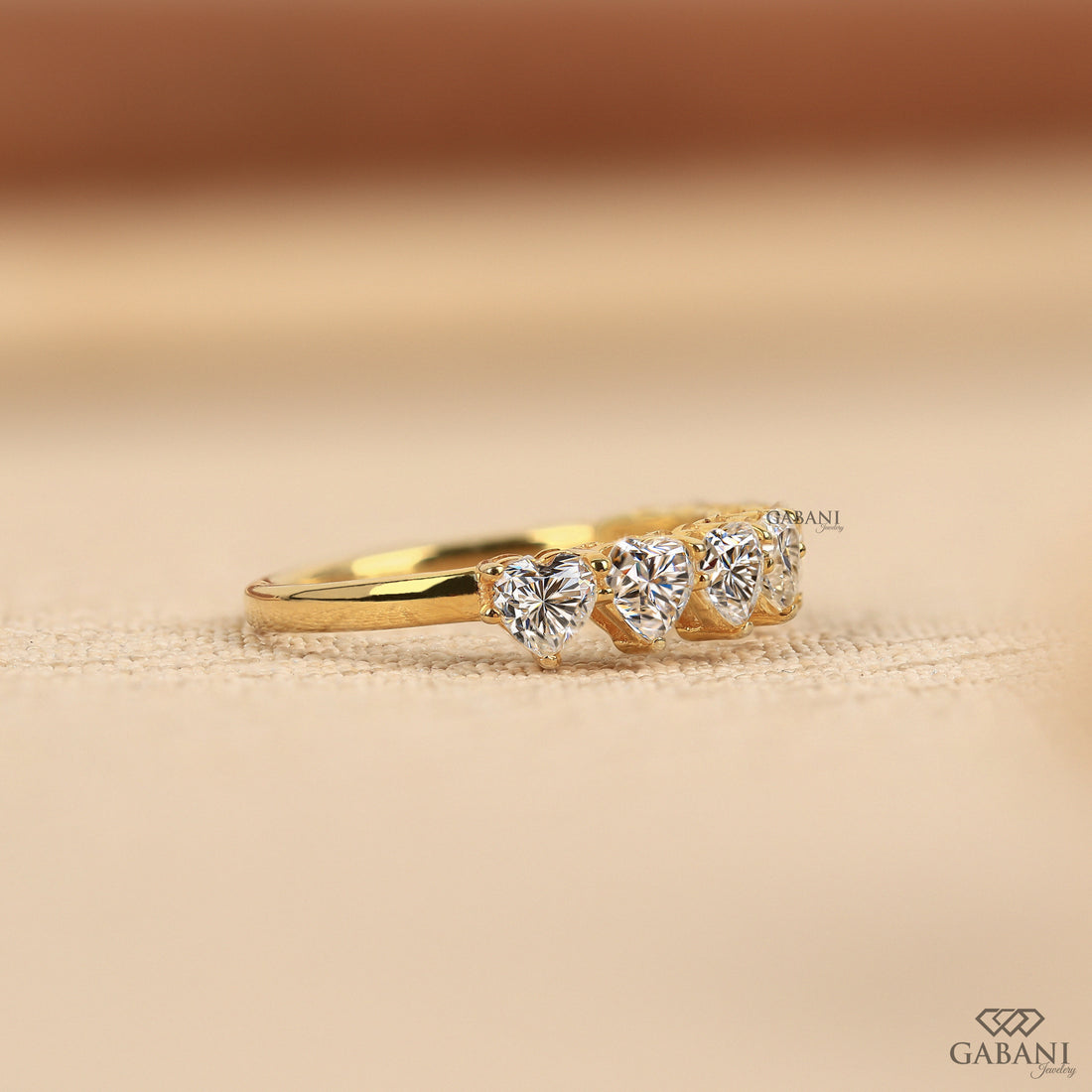 seven heart cut lab grown diamonds in a yellow gold half eternity wedding band with delicate prong settings.